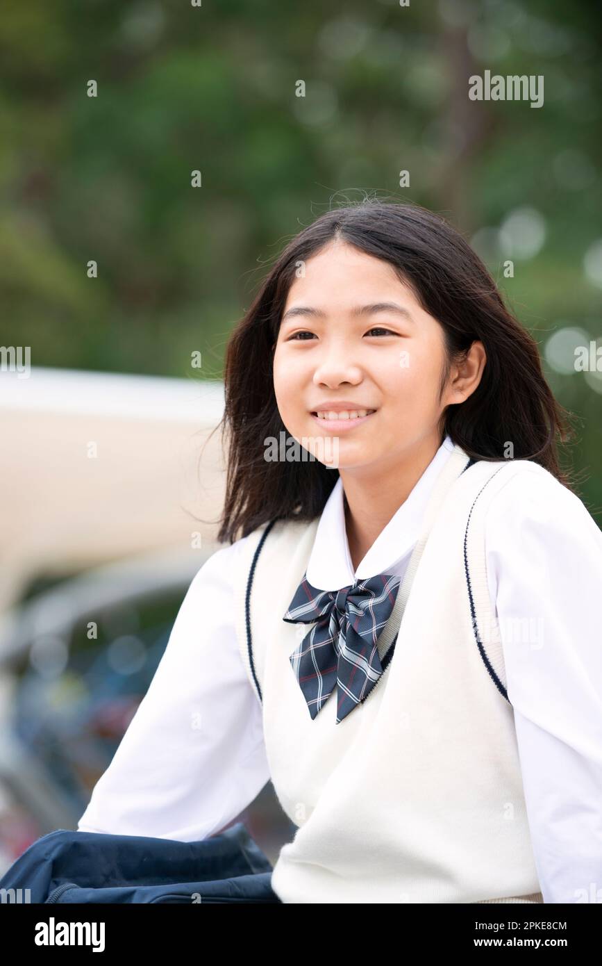 Studentessa in uniforme scolastica che guarda in lontananza e sorride Foto Stock
