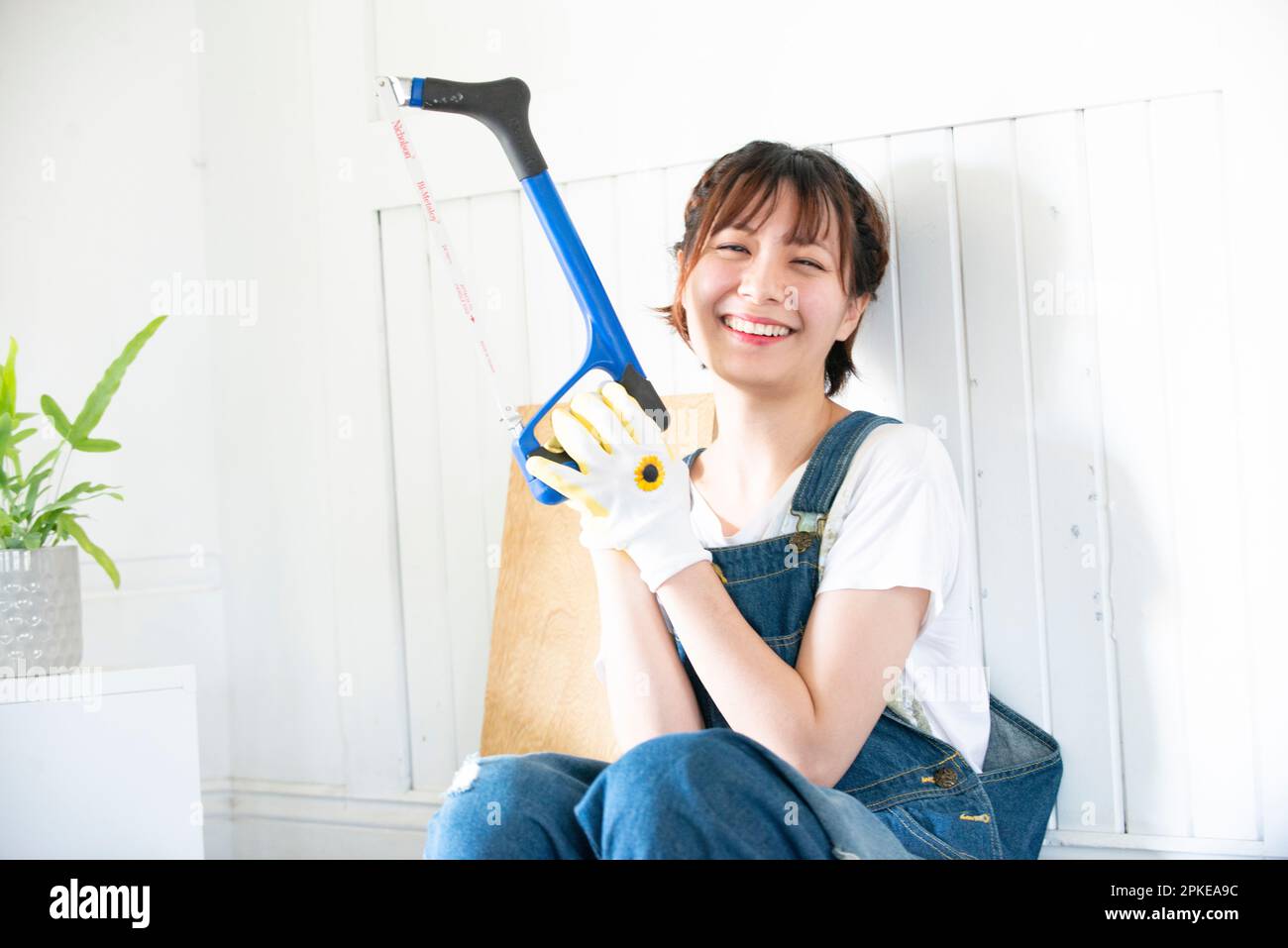 Donna che ride con un hacksaw Foto Stock