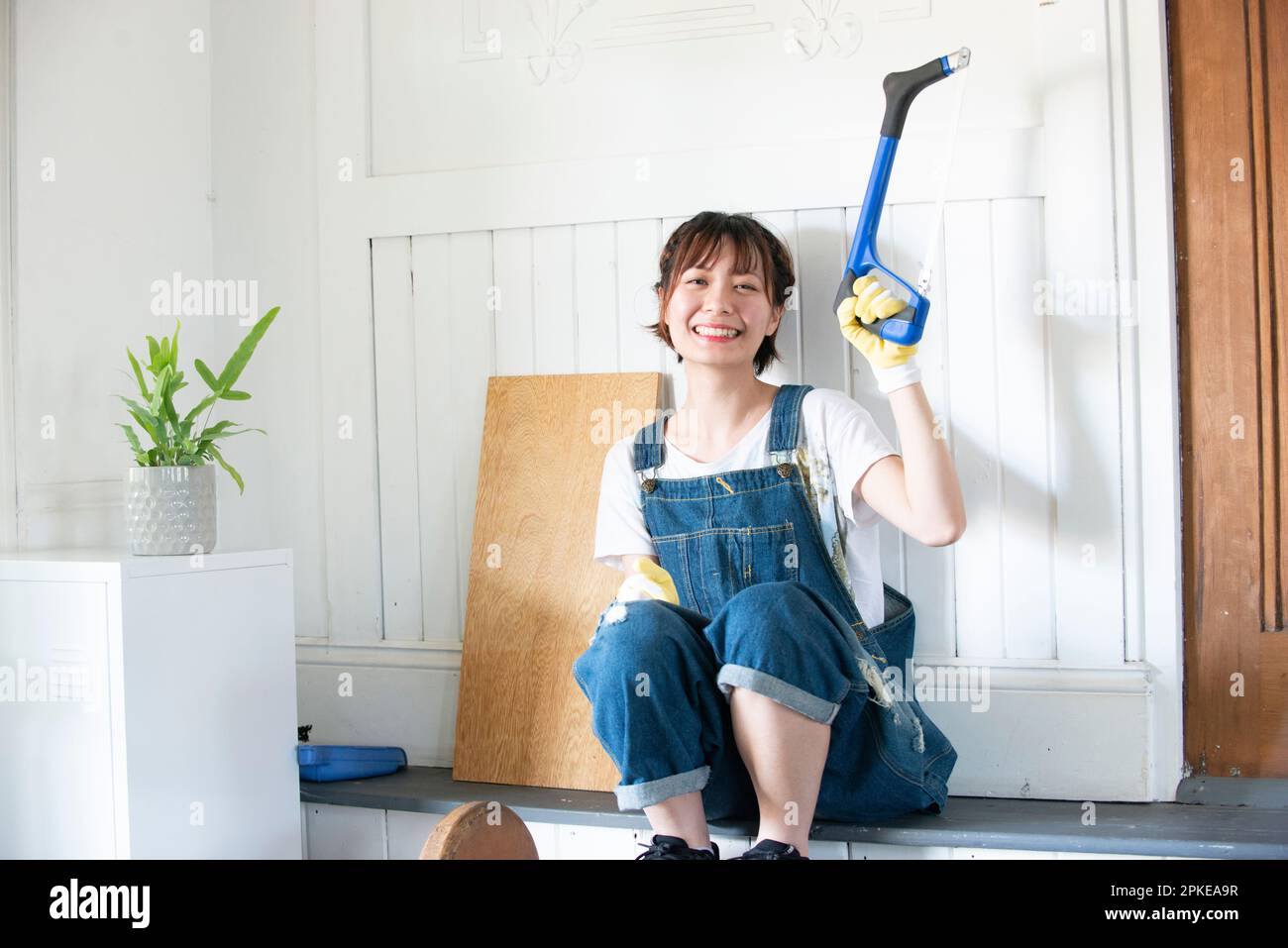 Donna che ride con un hacksaw Foto Stock