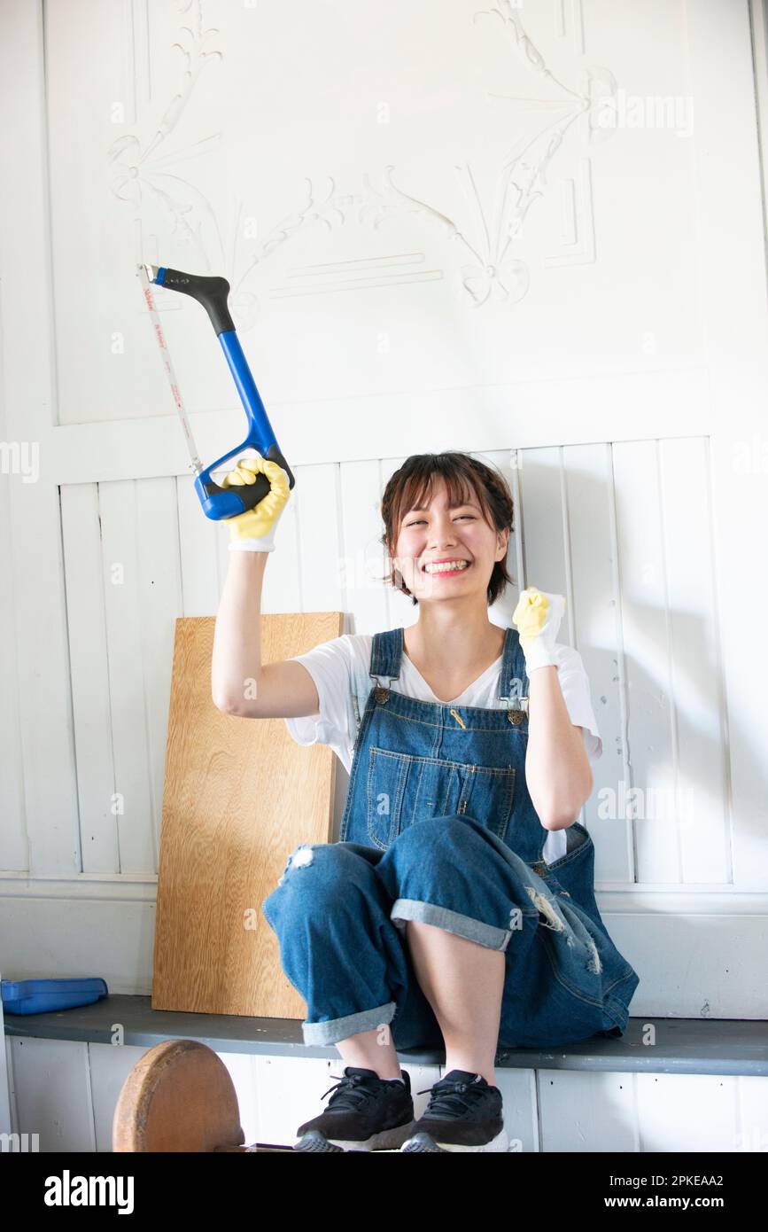 Donna che ride con un hacksaw Foto Stock