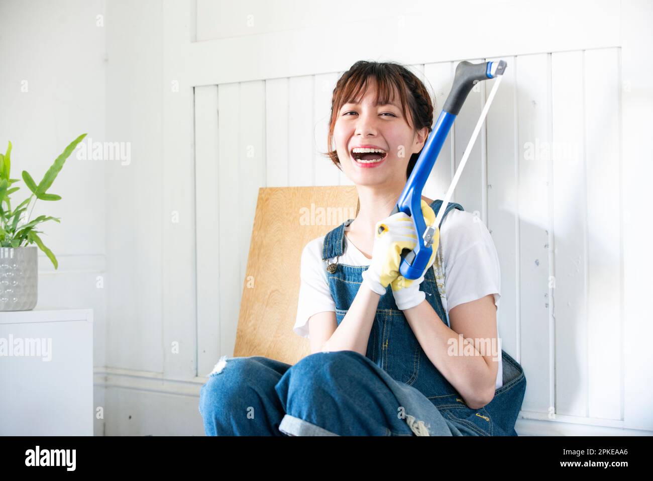 Donna che ride con un hacksaw Foto Stock