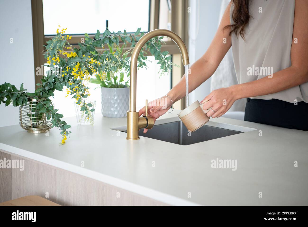 Donna lavaggio tazze in cucina isola Foto Stock