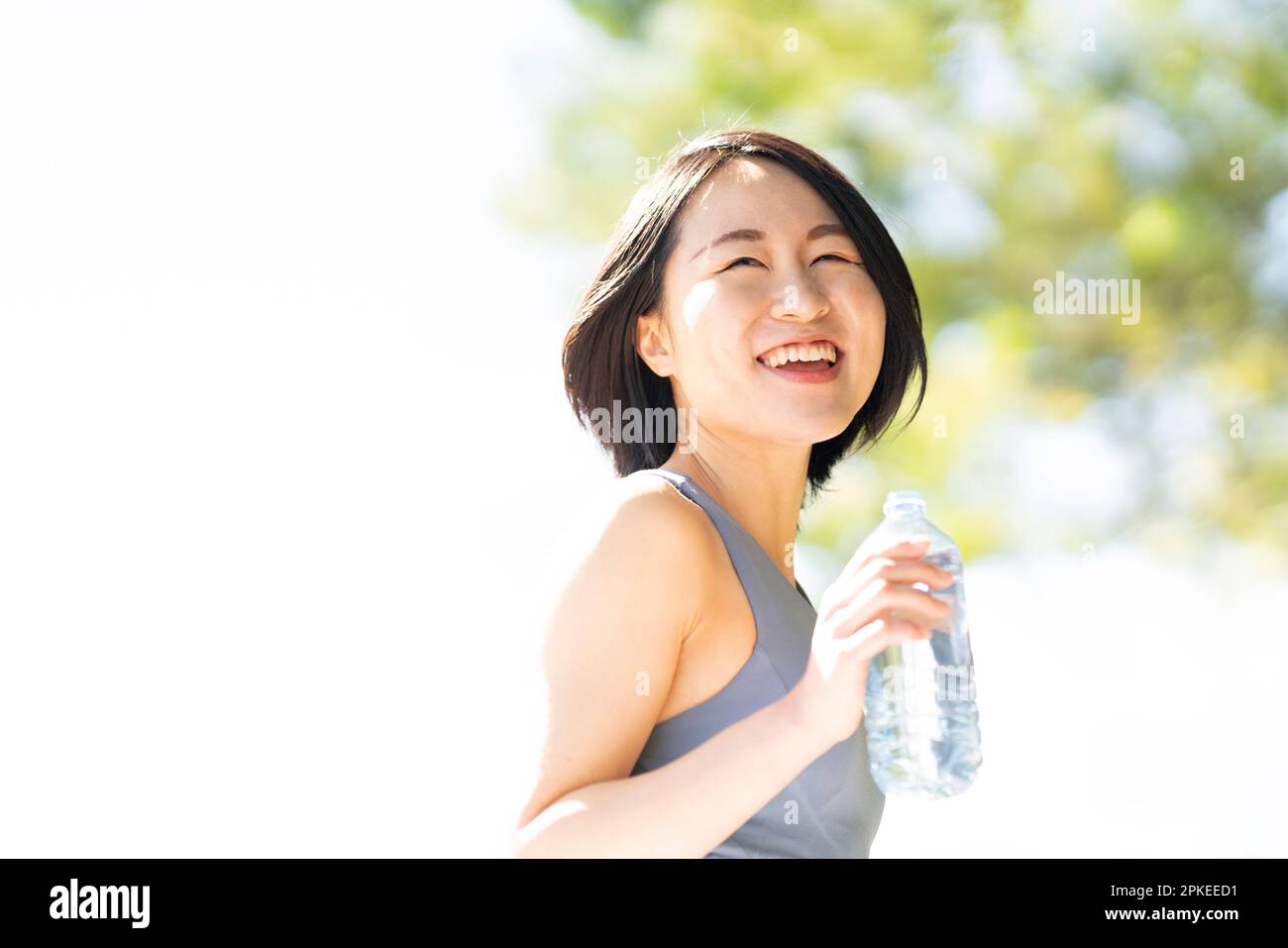 Donna che tiene una bottiglia d'acqua e ridendo Foto Stock