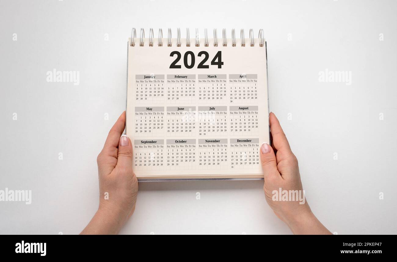Calendario anno 2024. le mani tengono il blocco note del calendario da tavolo 2024 su sfondo bianco. Piani per il nuovo anno per il 2024. piano di obiettivo, concetto di obiettivo, piano di azione, Foto Stock
