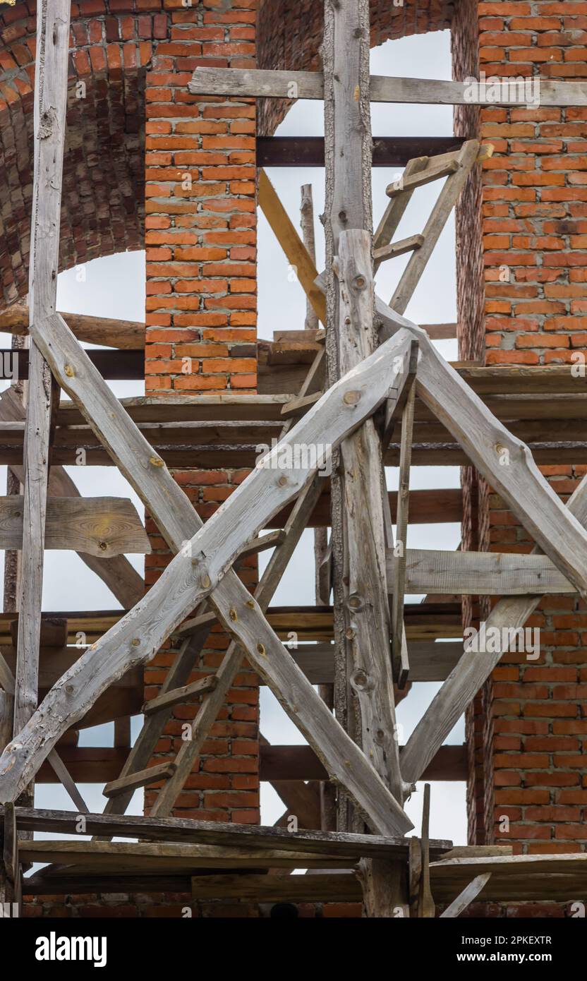 costruzione di un campanile e di una chiesa. Muro di mattoni. Ponteggi in legno Foto Stock