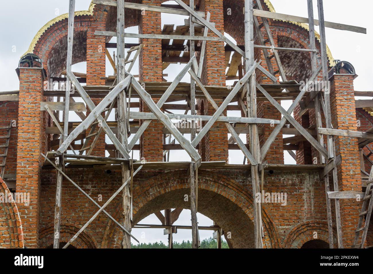 costruzione di un campanile e di una chiesa. Muro di mattoni. Ponteggi in legno Foto Stock