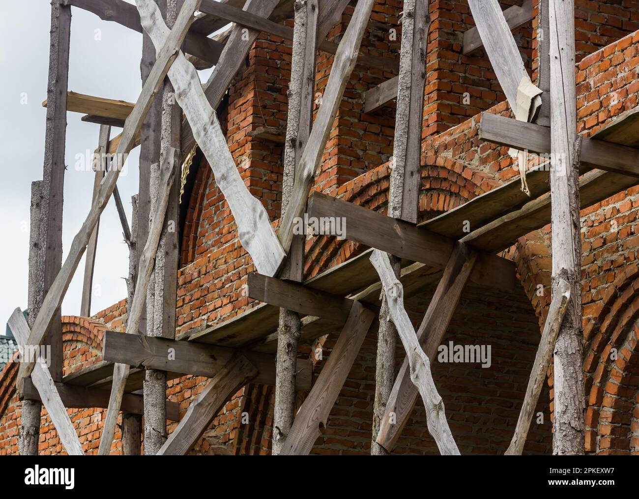 costruzione di un campanile e di una chiesa. Muro di mattoni. Ponteggi in legno Foto Stock