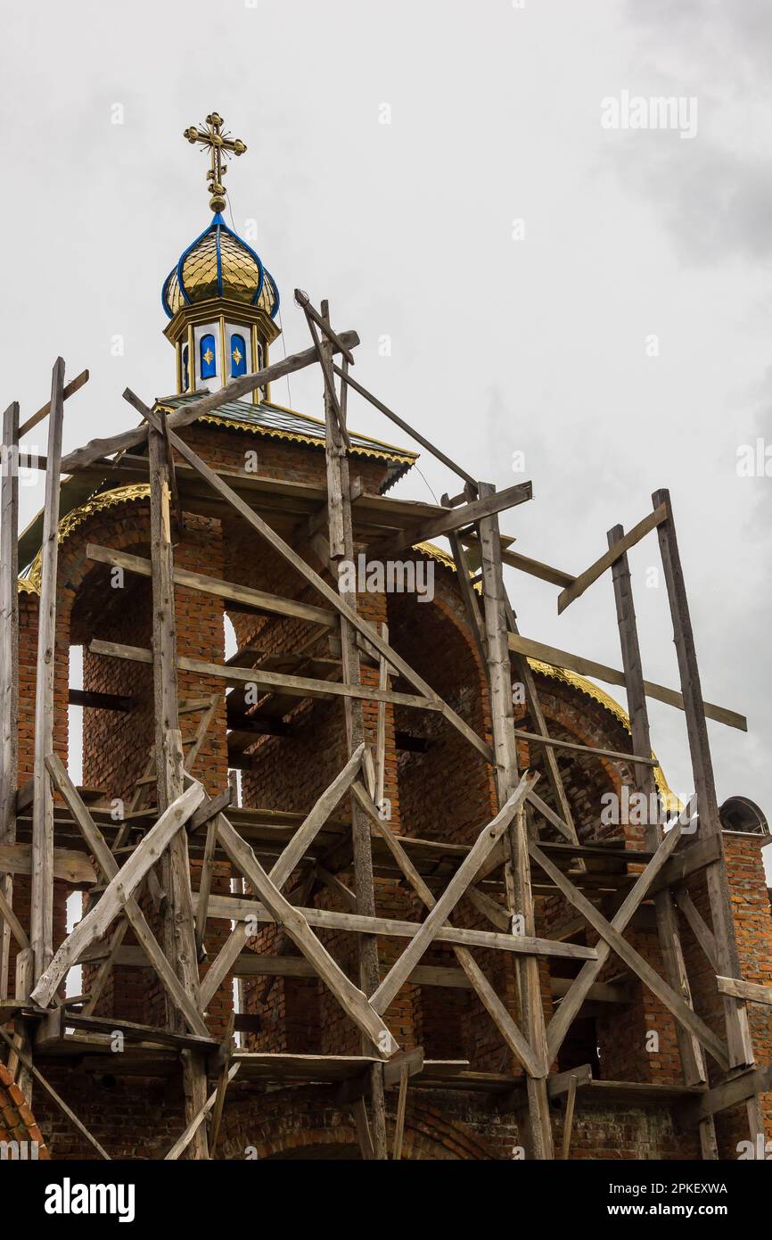 costruzione di un campanile e di una chiesa. Muro di mattoni. Ponteggi in legno Foto Stock