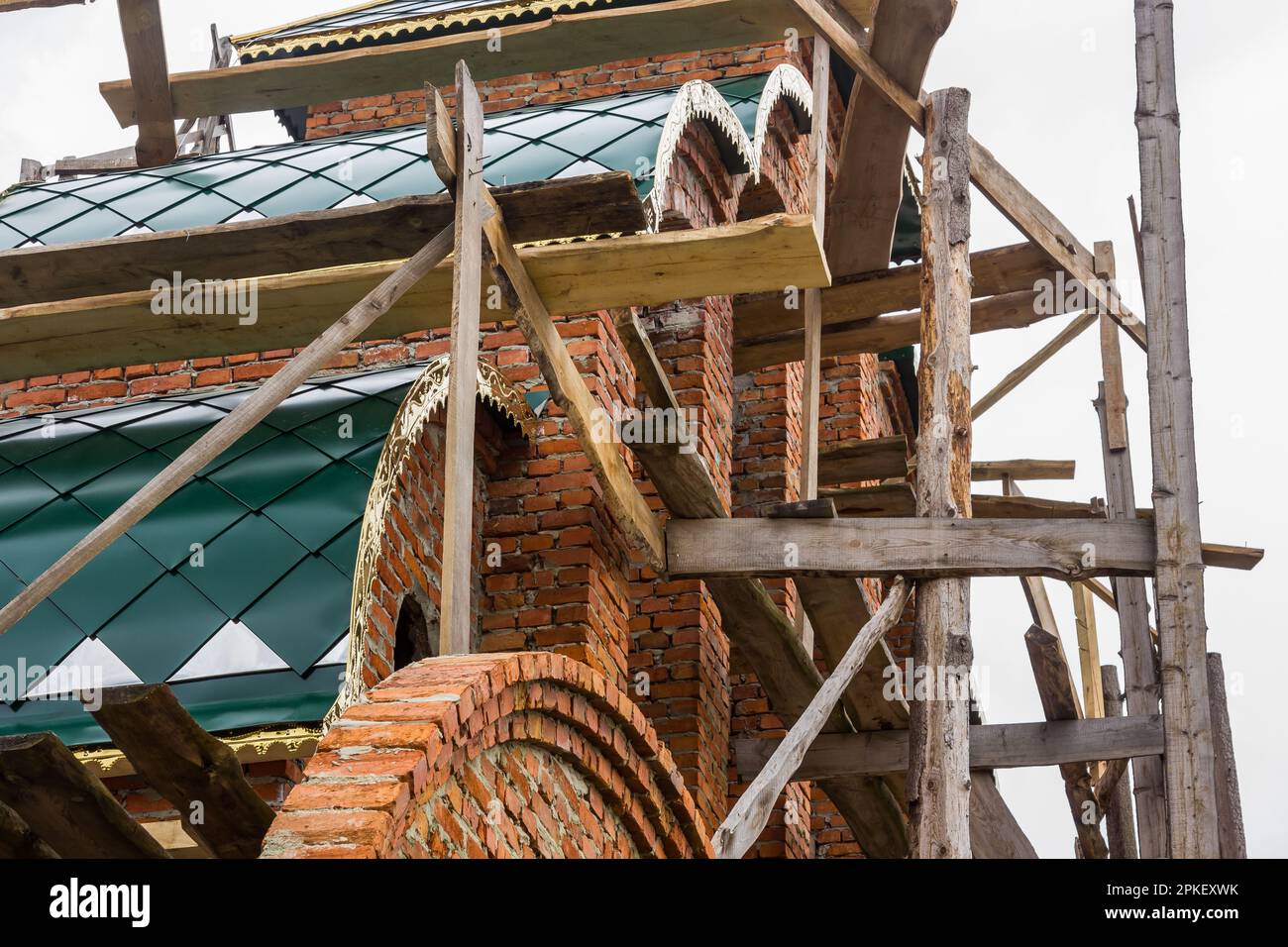 costruzione di un campanile e di una chiesa. Muro di mattoni. Ponteggi in legno Foto Stock