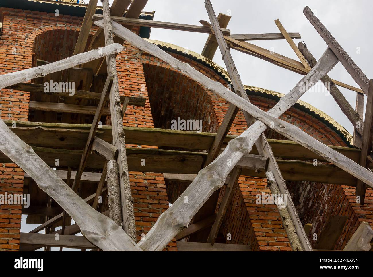costruzione di un campanile e di una chiesa. Muro di mattoni. Ponteggi in legno Foto Stock