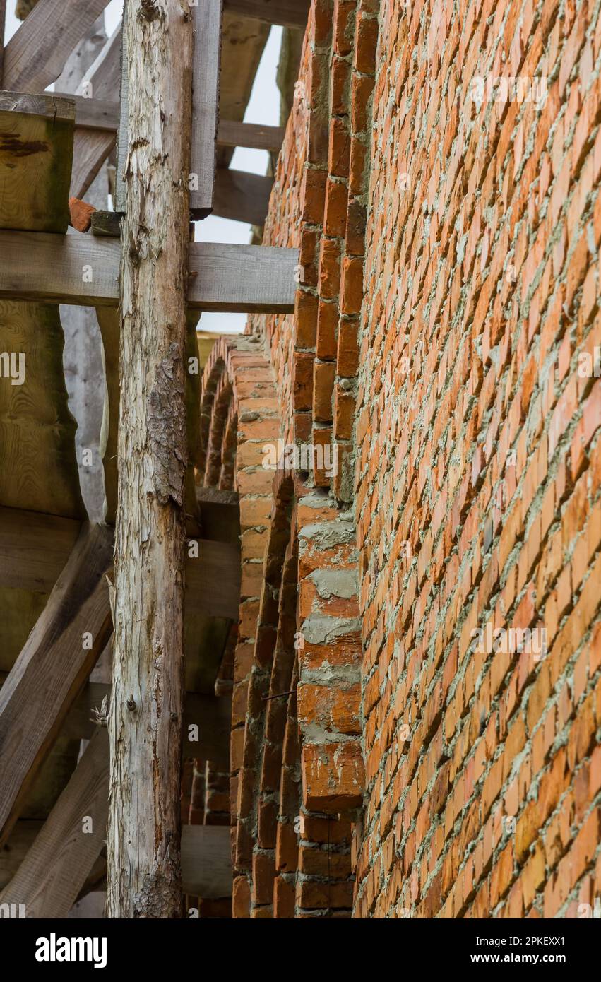 costruzione di un campanile e di una chiesa. Muro di mattoni. Ponteggi in legno Foto Stock