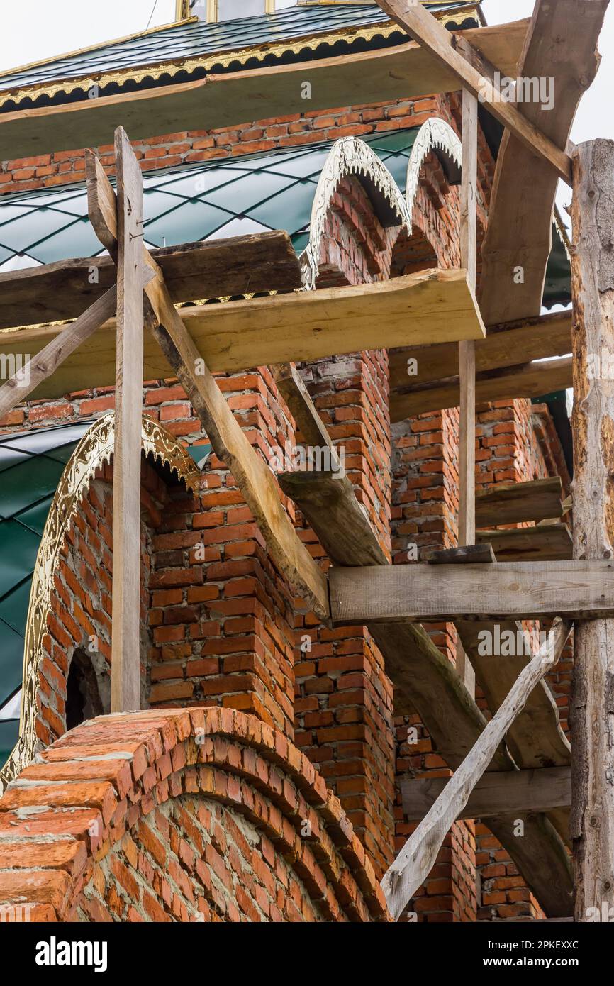 costruzione di un campanile e di una chiesa. Muro di mattoni. Ponteggi in legno Foto Stock