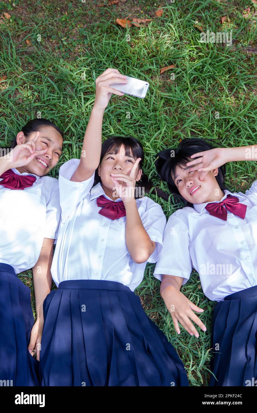Studenti delle scuole superiori che scattano una foto sdraiata sull'erba Foto Stock