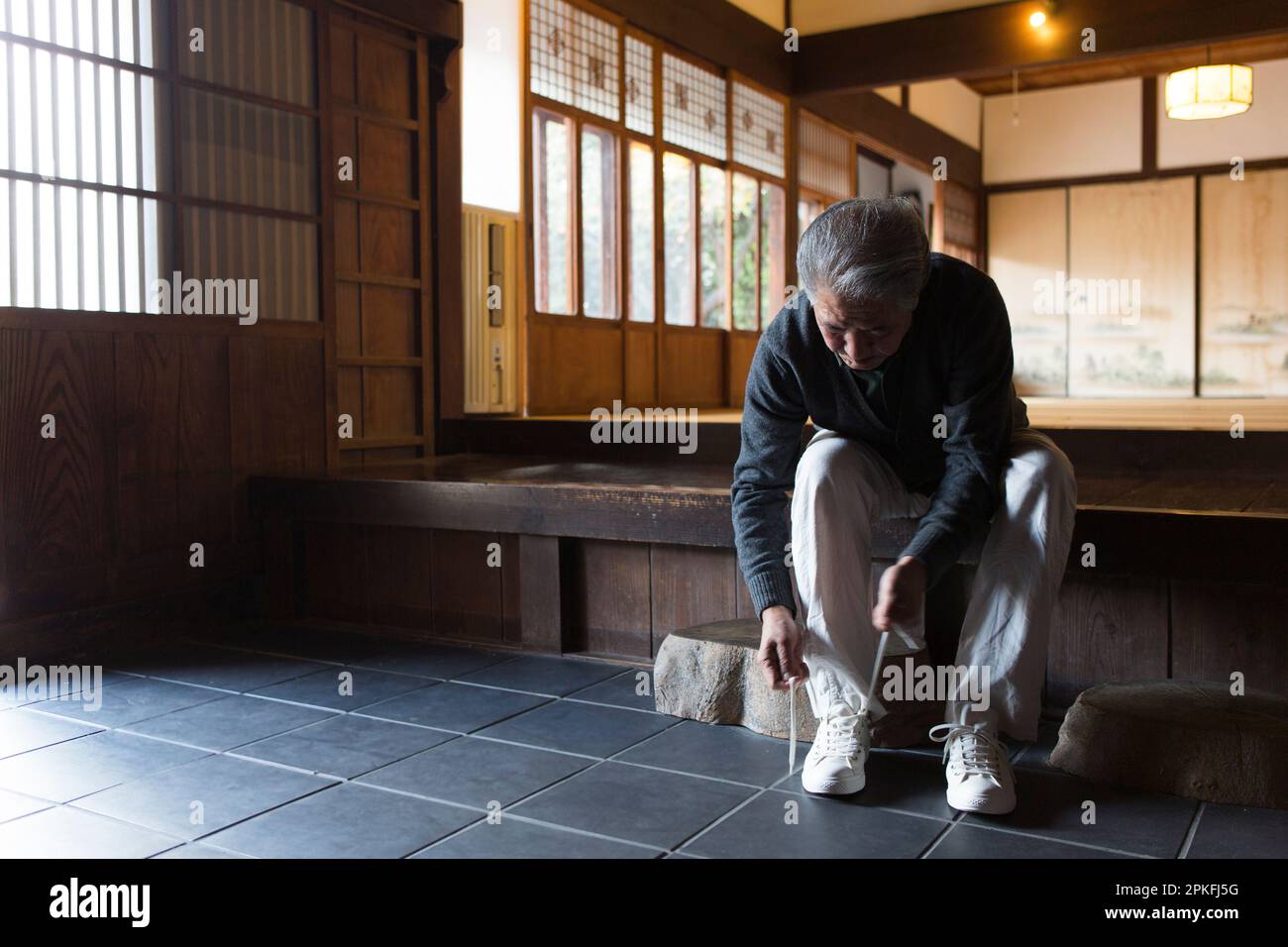 Uomo anziano che legava le scarpe alla porta d'ingresso Foto Stock