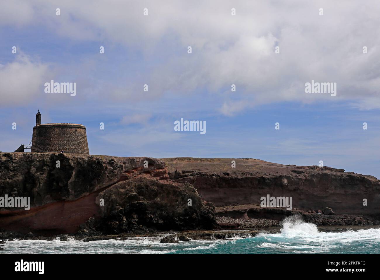 La cima della scogliera e le onde atlantiche che si infrangono alla torre dell'area di Torre del Aguila-Castillo De Las Coloradas, Lanzarote, Isole Canarie, Spagna Foto Stock