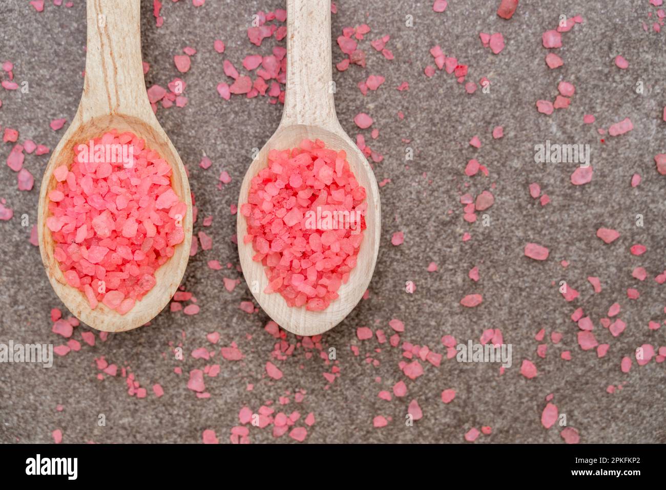 Due cucchiai di legno con sale marino rosa primo piano Foto Stock