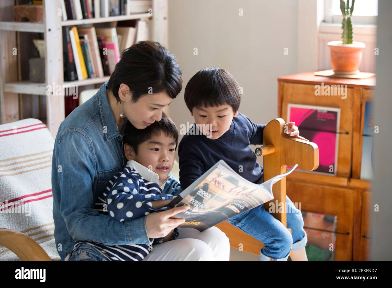 Madre e ragazzi che leggono una rivista nel soggiorno Foto Stock