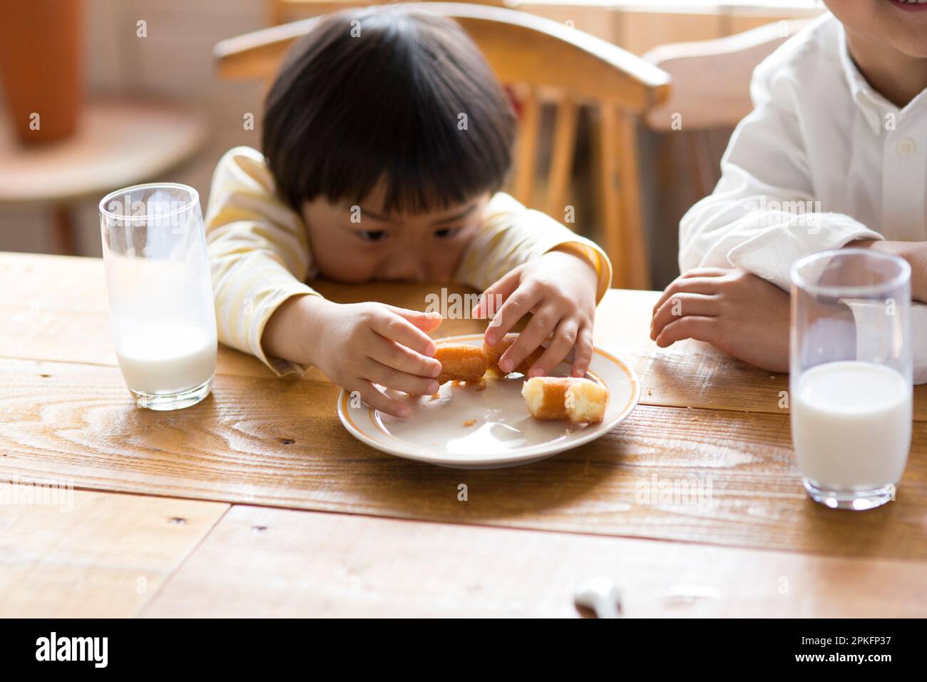 Bambino che mangia le ciambelle al tavolo della cucina Foto Stock