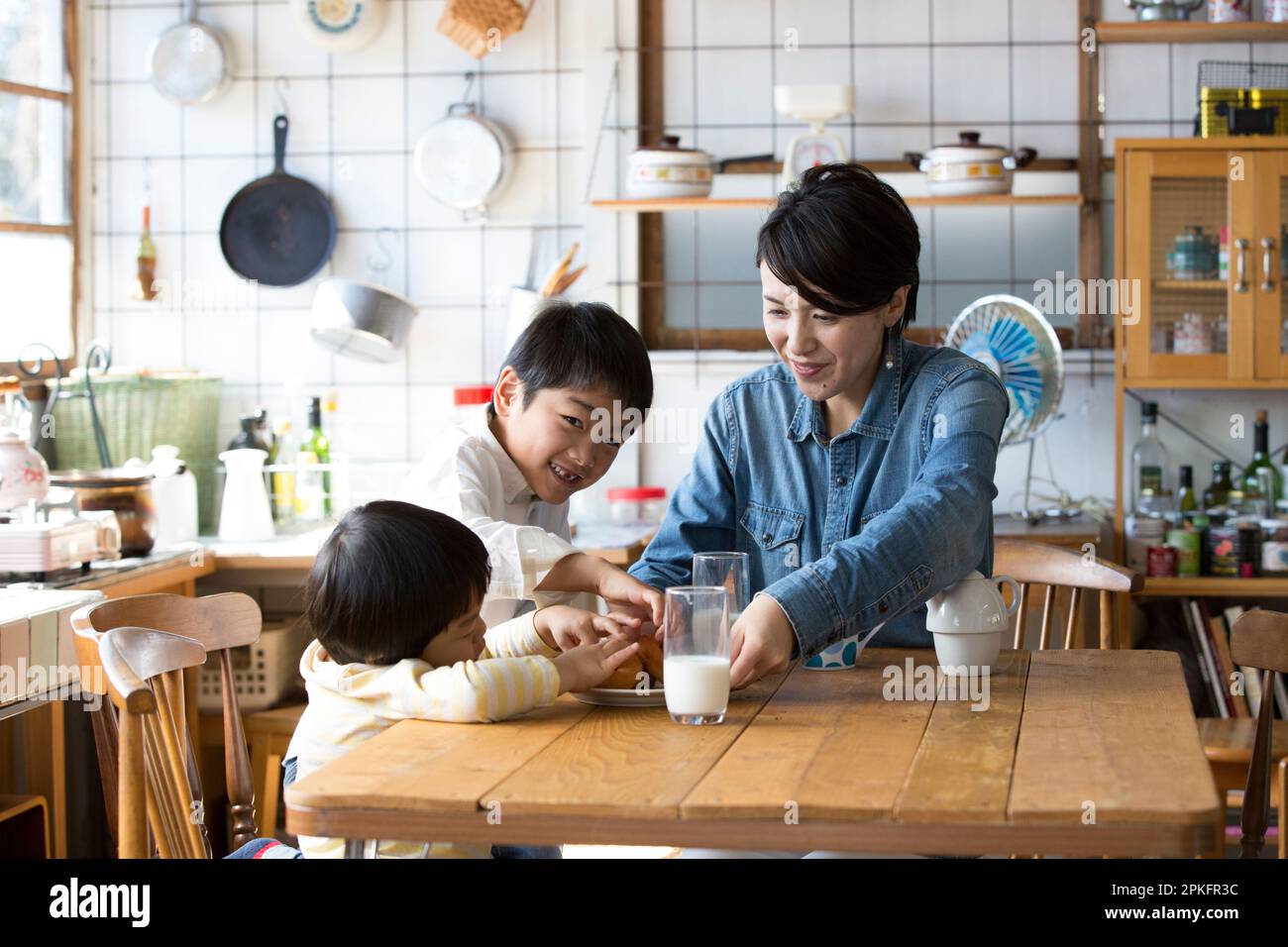Fratello e madre mangiano le ciambelle al tavolo della cucina Foto Stock