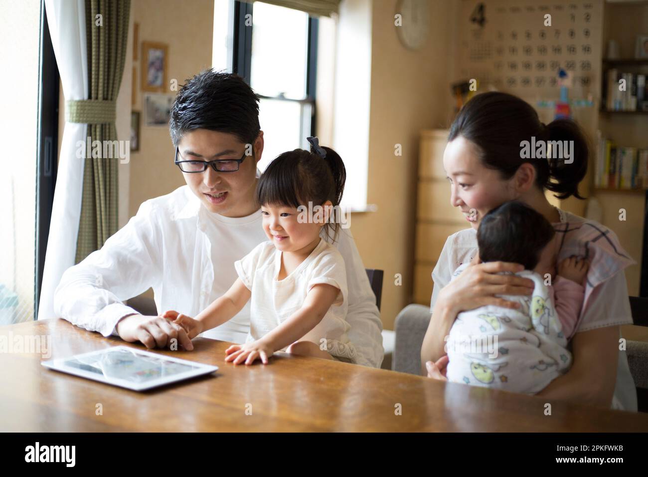 La famiglia utilizza un tablet nel soggiorno Foto Stock