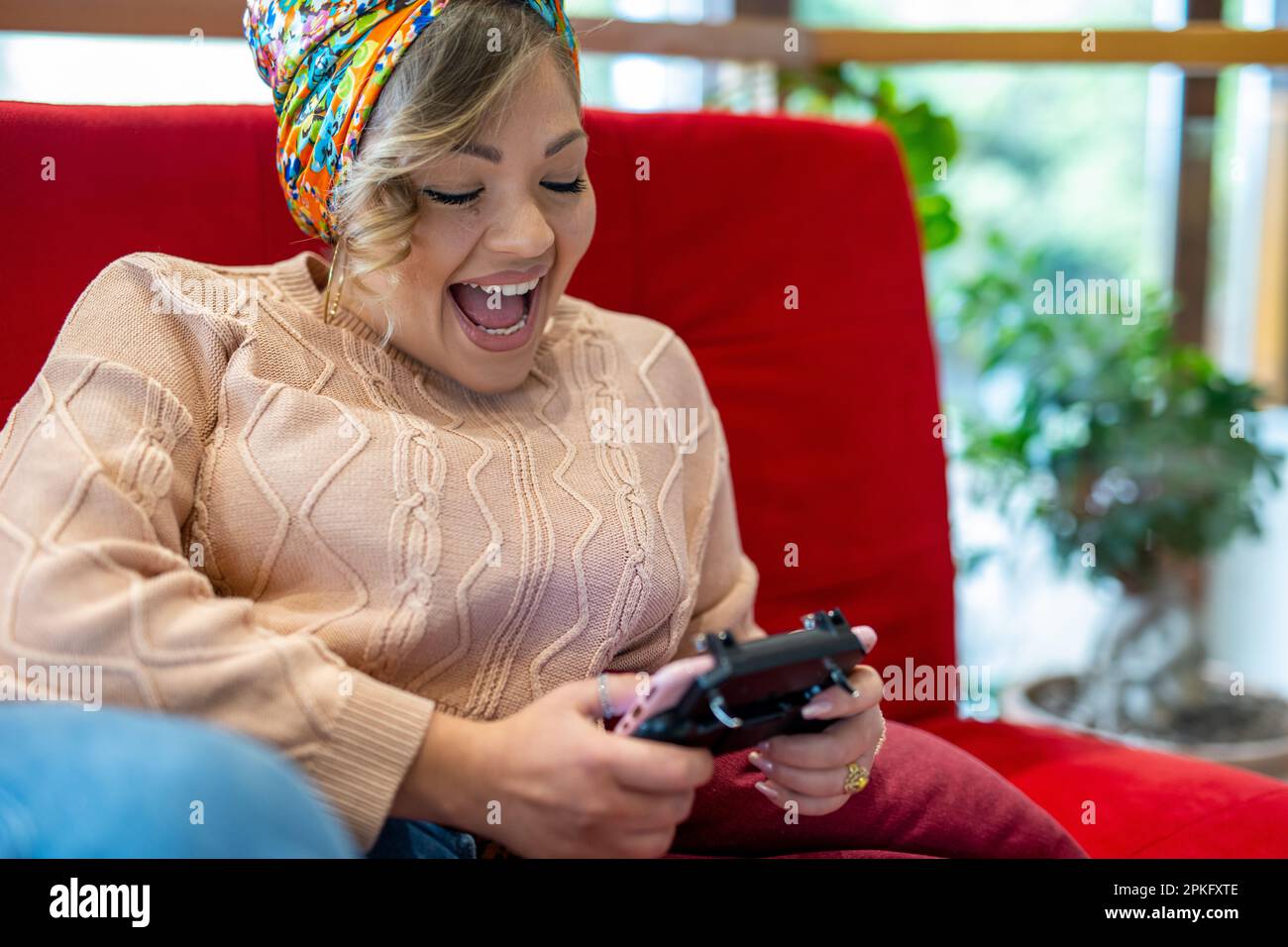 Giovane donna felice curvy che controlla i social media tenendo lo smartphone a casa, donna sorridente utilizzando l'app del telefono cellulare giocare, fare acquisti online, ordinare Foto Stock