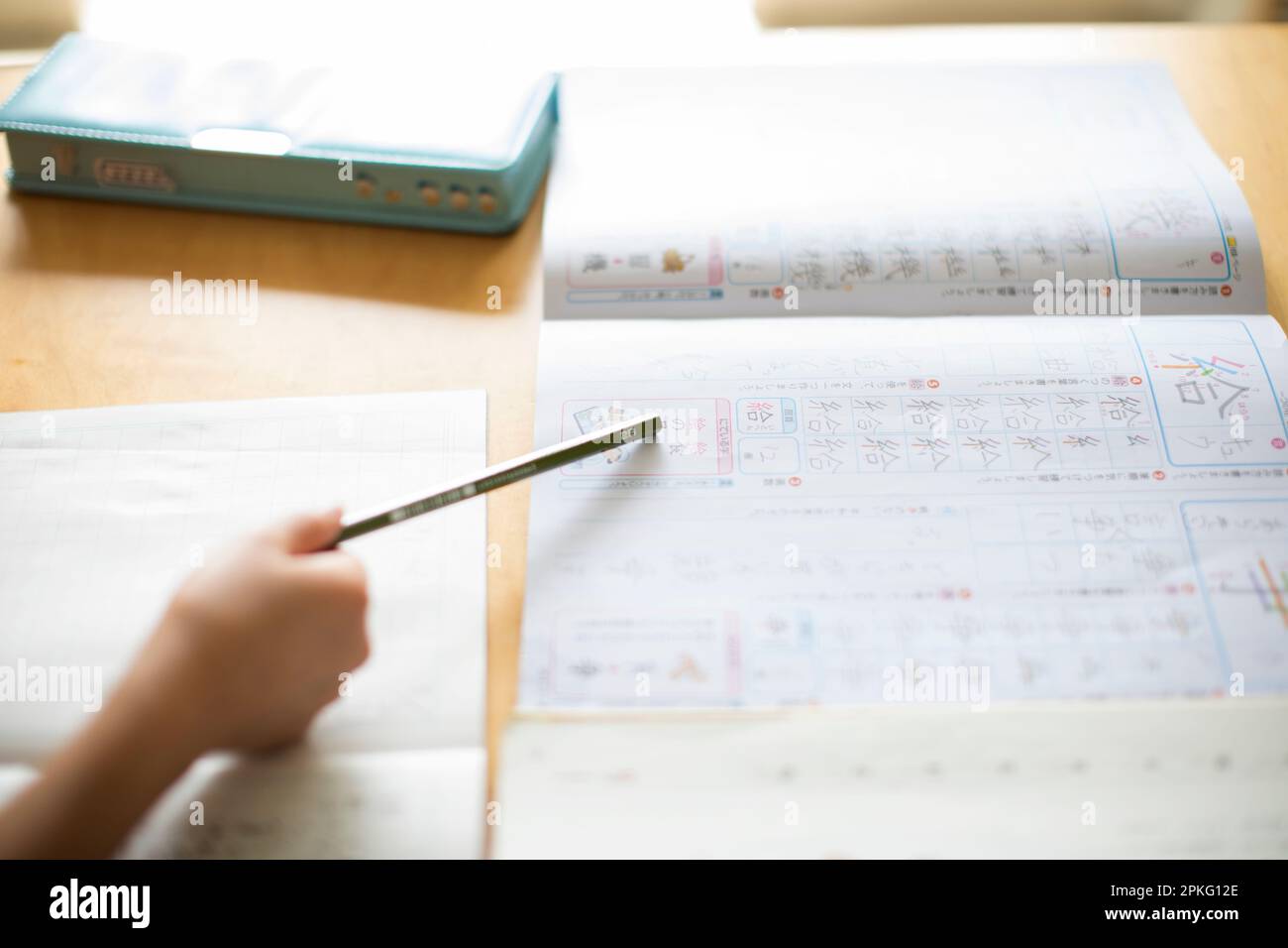 Un bambino che indica un testo Kanji con una matita Foto Stock