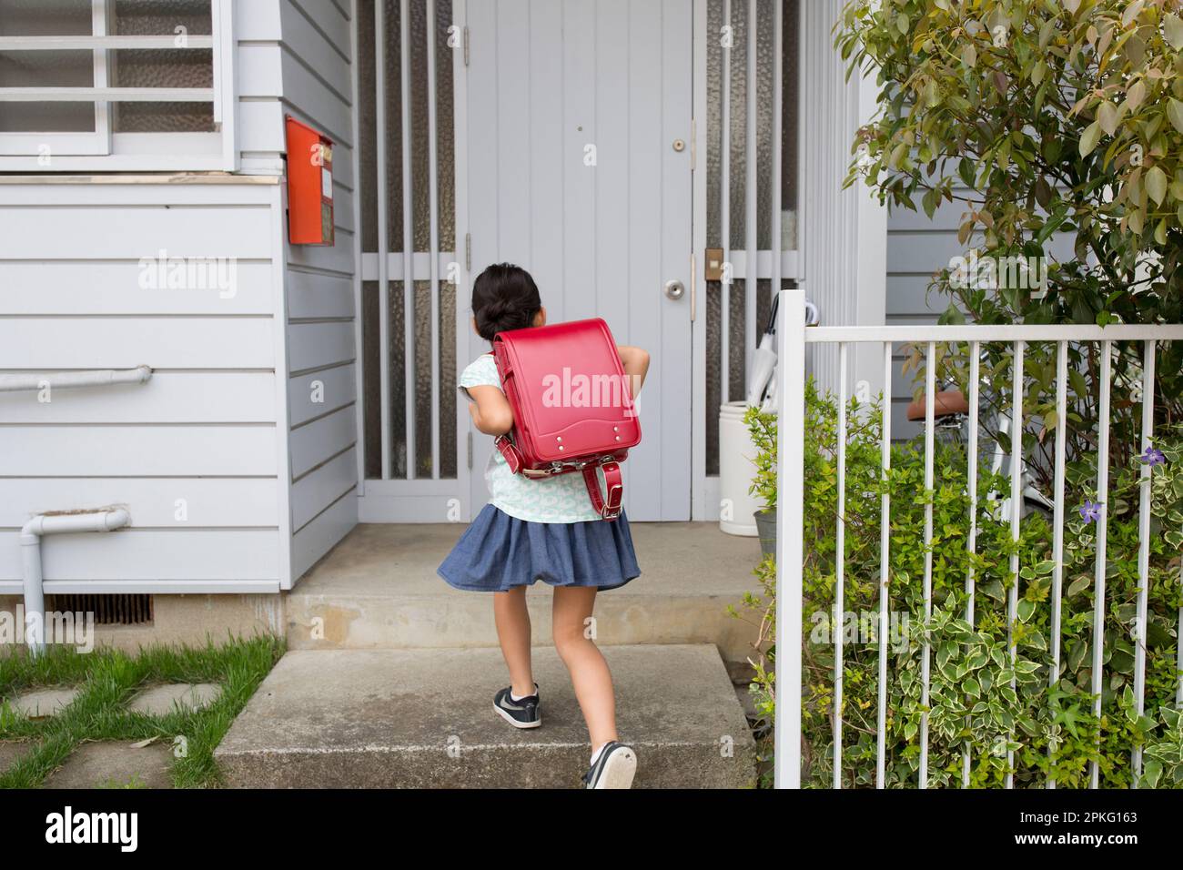 Una bambina della scuola elementare che porta la borsa della scuola a casa Foto Stock