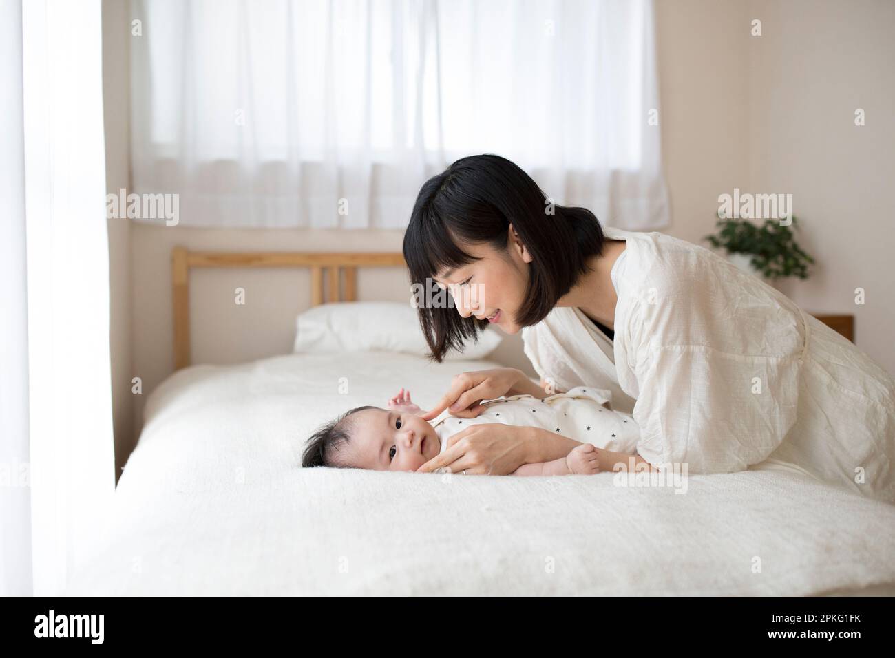 Bambino sdraiato sul letto con madre che conforta il bambino Foto Stock