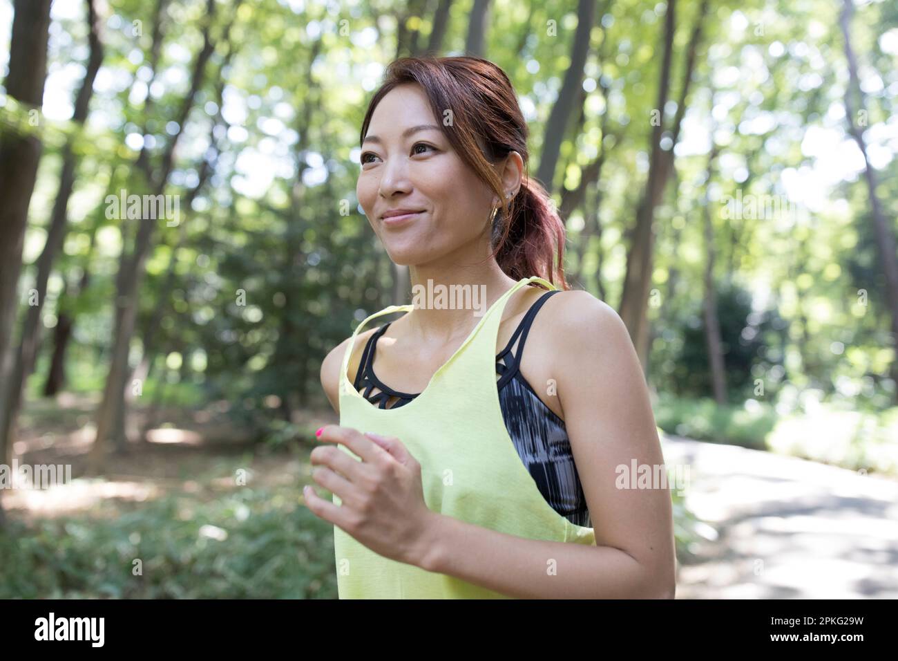 Donna che fa jogging tra gli alberi Foto Stock