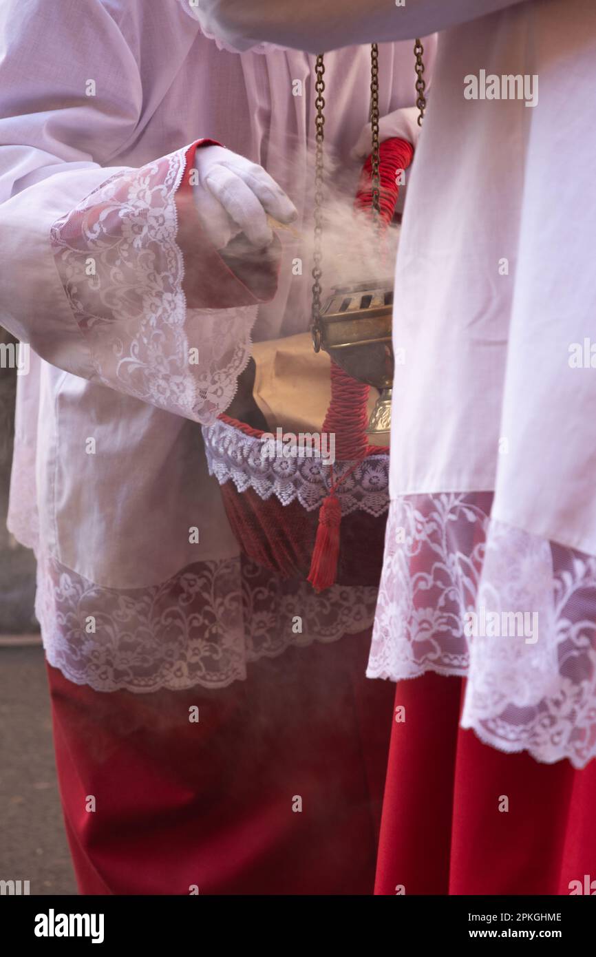 Madrid, Spagna; 2 aprile 2023: Processione della settimana Santa nella Domenica delle Palme. Primo piano dei ragazzi dell'altare che illuminano incenso su un bruciatore. Foto Stock