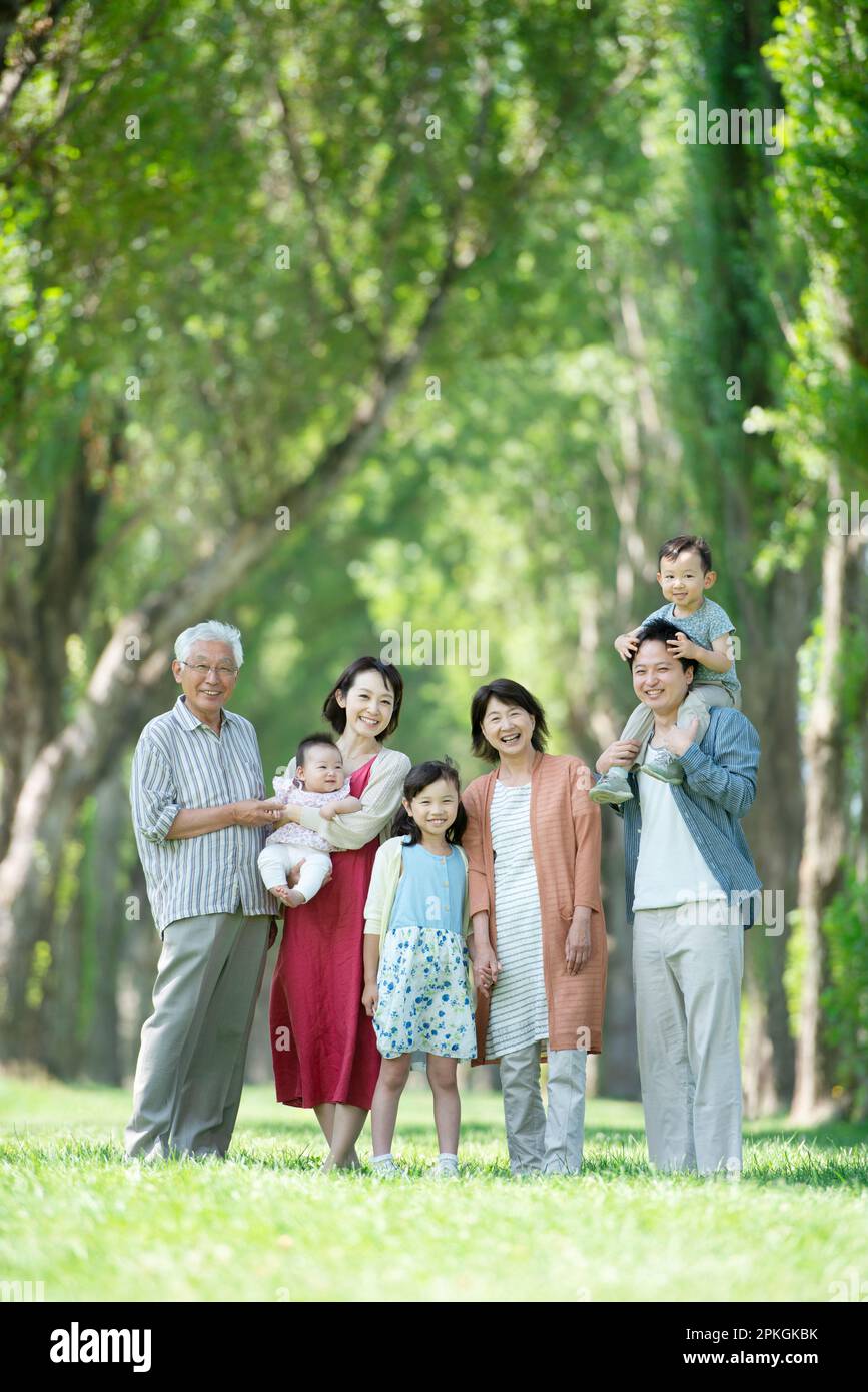 Una famiglia di tre generazioni sorridente ad una fila di pioppi Foto Stock