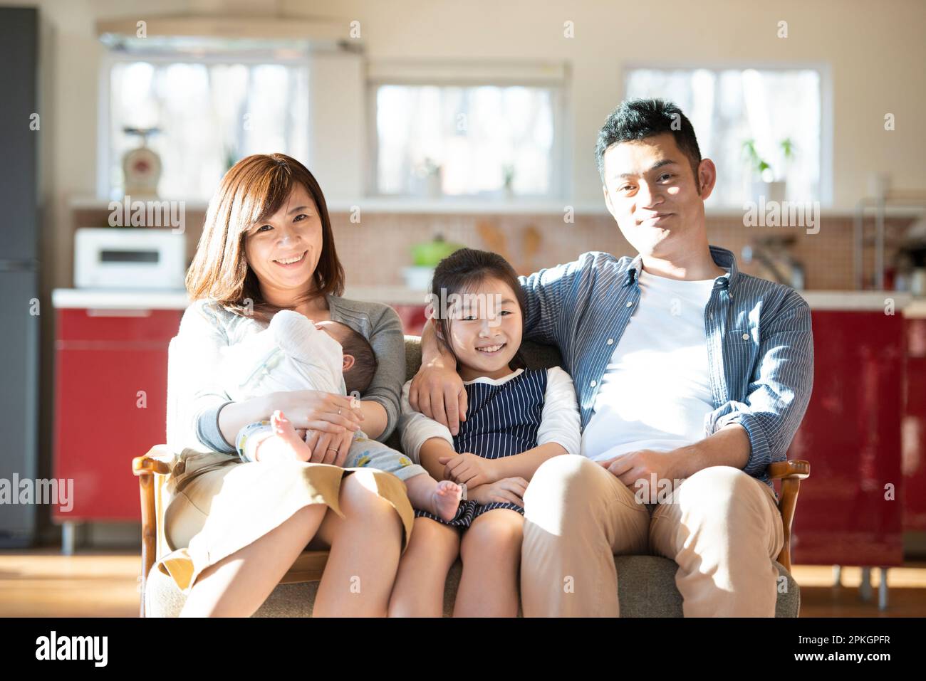 Famiglia seduta sul divano e sorridente Foto Stock