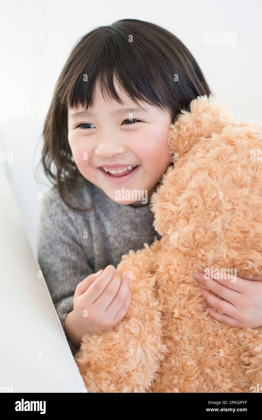 Una ragazza che tiene un orso ripieno e sorridente Foto Stock