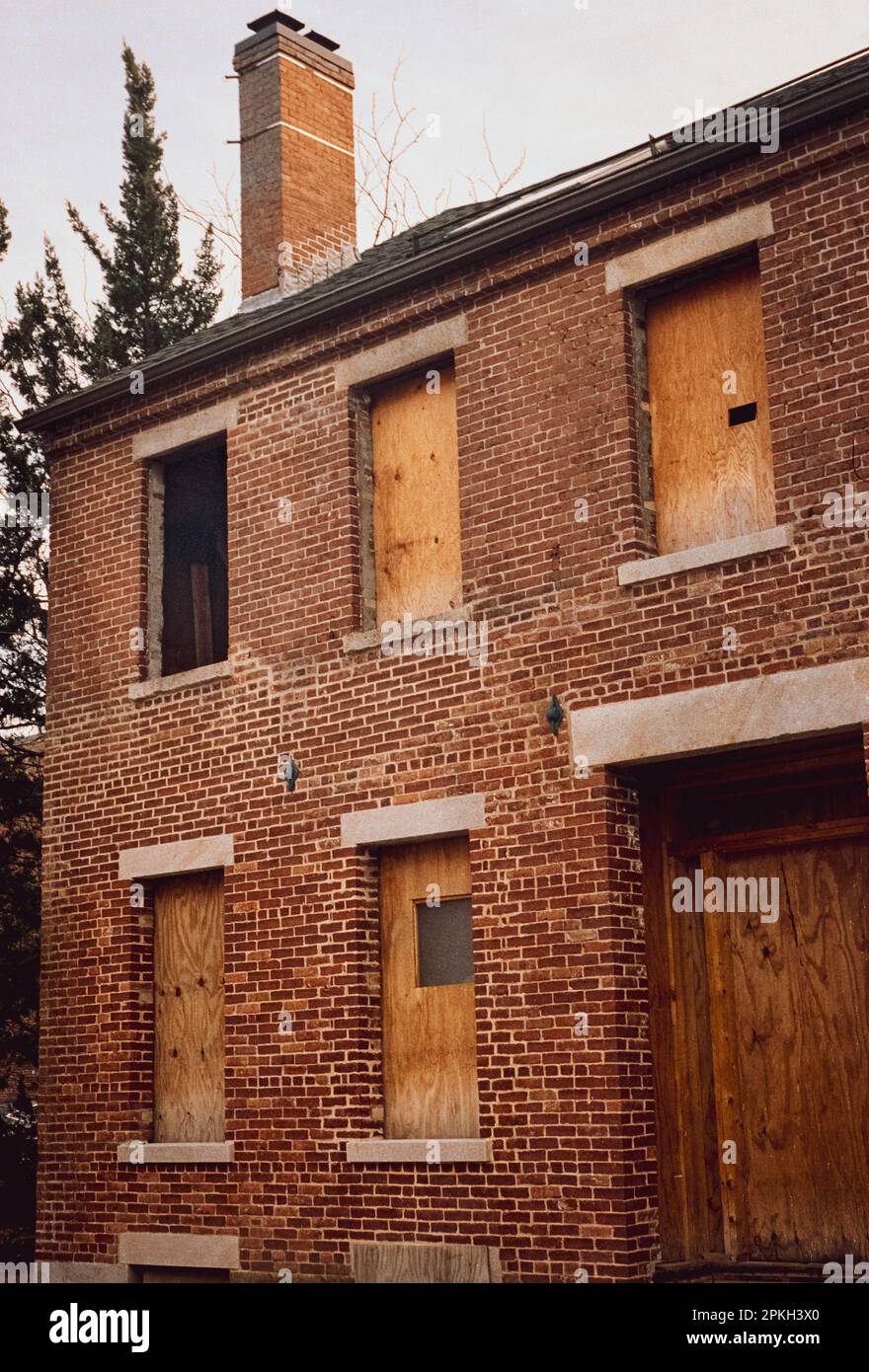 Una casa in mattoni sfinestrati in fase di ricostruzione con finestre a bordo si trova nella sezione storica di Lowell, Massachusetts durante l'ora d'oro. L'ima Foto Stock