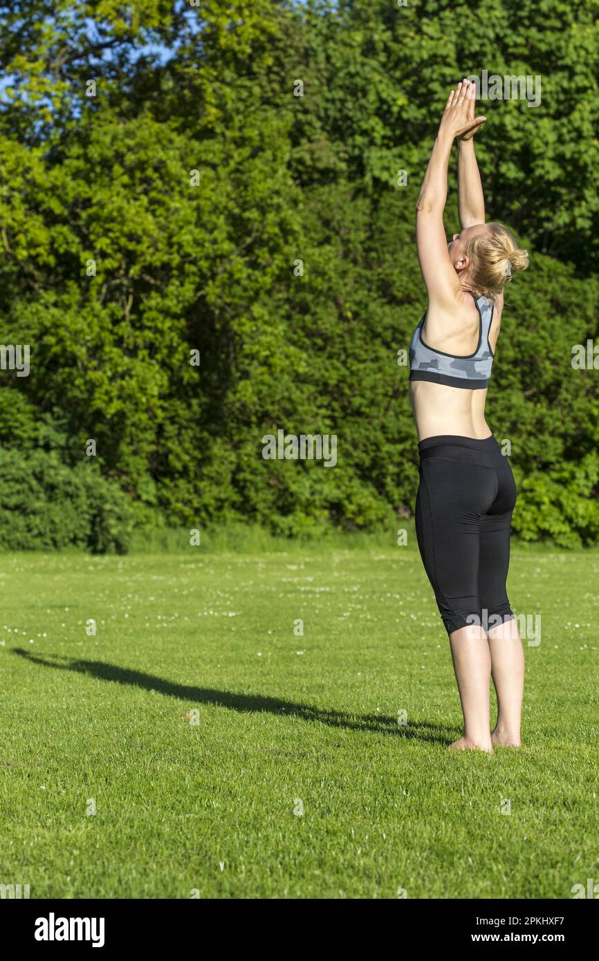 Donna (38) fare yoga in un prato nel parco, Kiel, Schleswig-Holstein, Germania Foto Stock