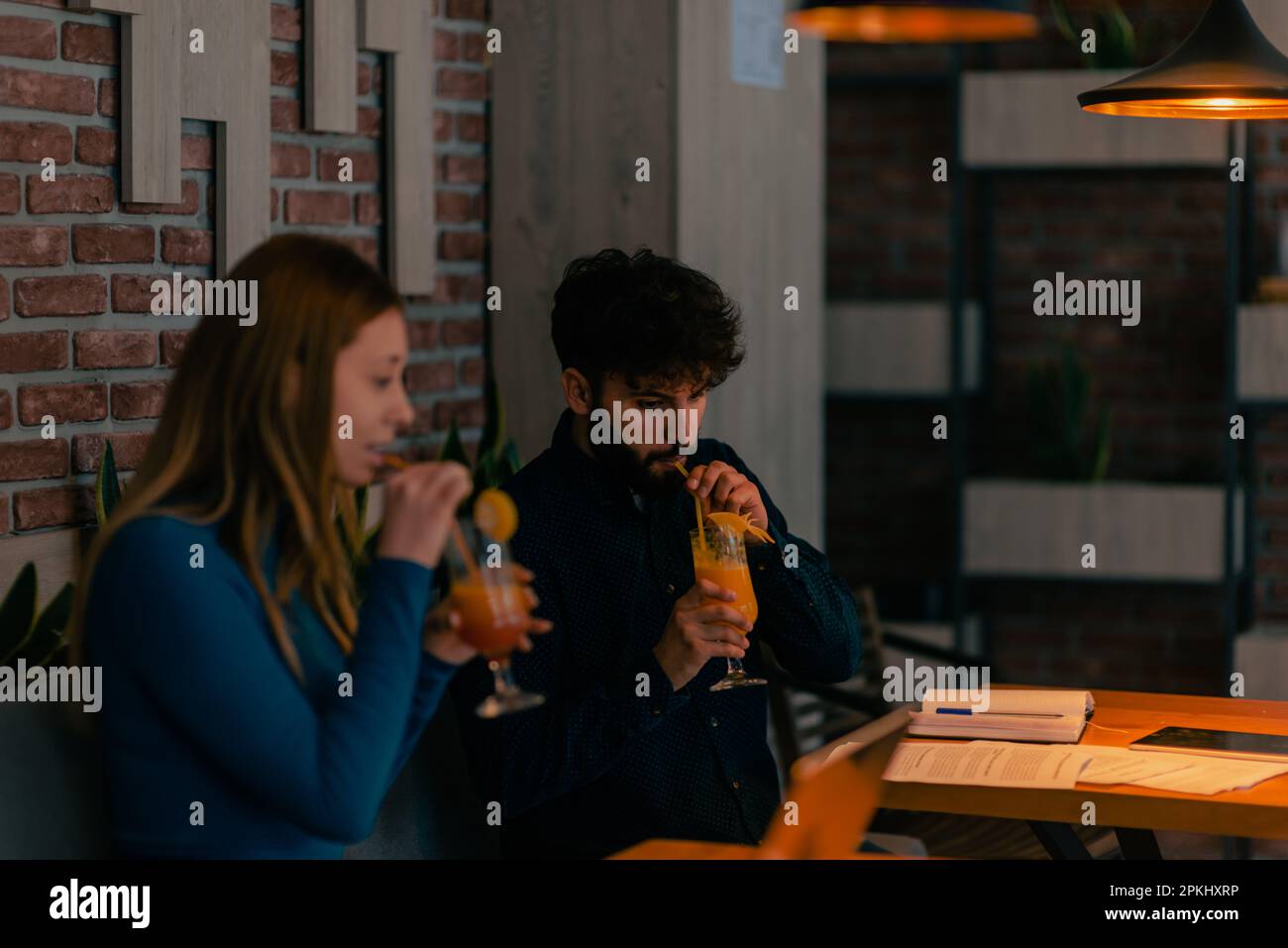 Coppia simpatica seduta insieme al caffè, sorridente parlando e bevendo i loro cocktail al caffè Foto Stock