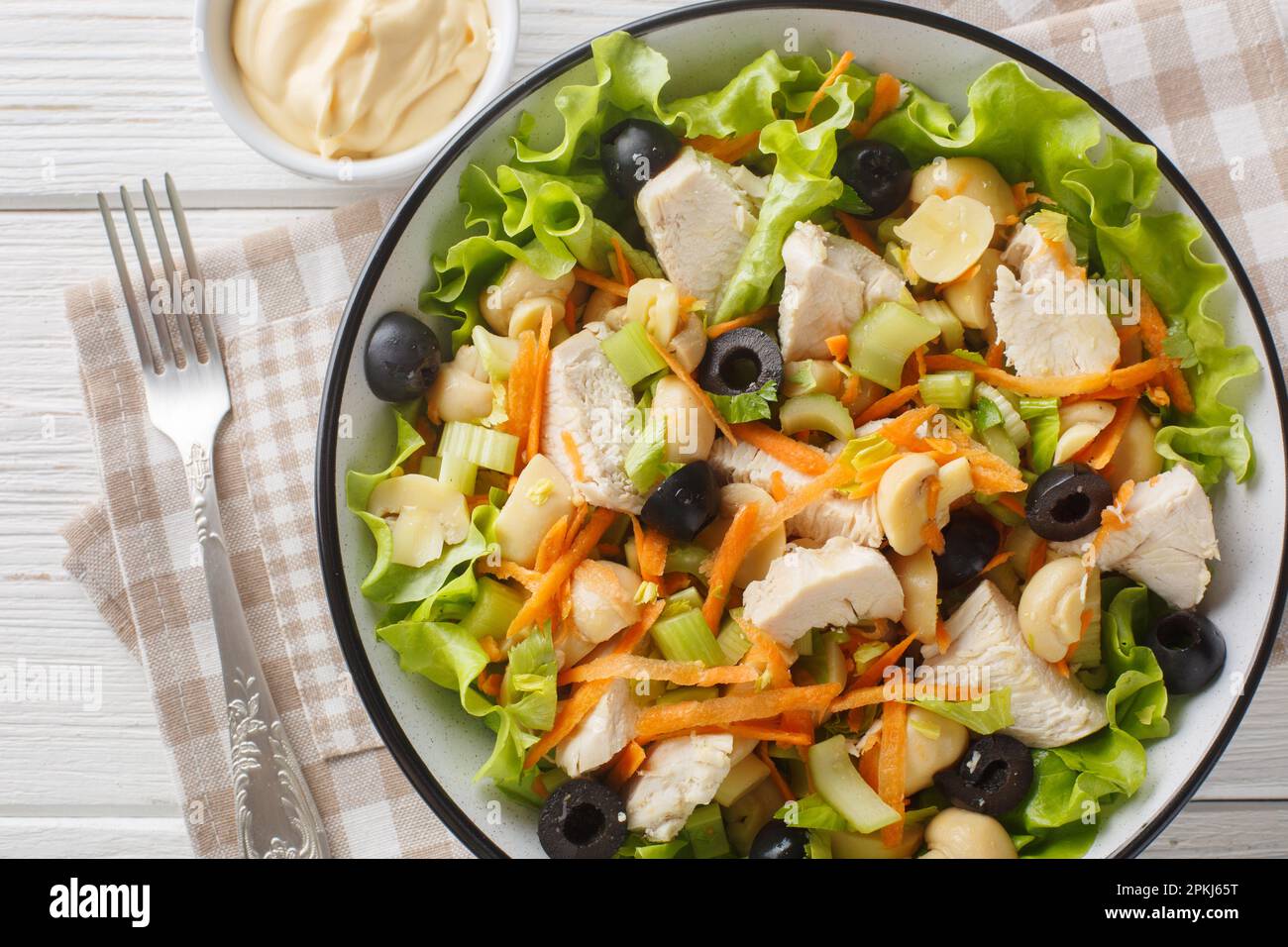 Insalata di dieta sana con pollo, funghi, carote, sedano, olive, primo piano con formaggio e lattuga in una ciotola su un tavolo di legno. Vista orizzontale dall'alto da Foto Stock