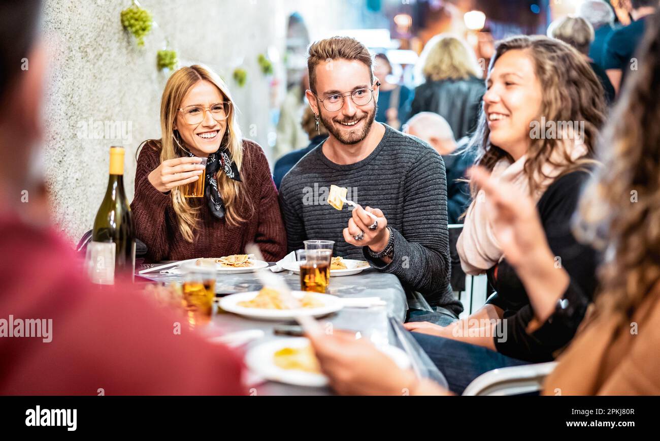 Persone alla moda che si divertono a bere vino bianco durante un evento Street food - amici felici che mangiano piatti locali al ristorante all'aperto insieme - Food and Foto Stock