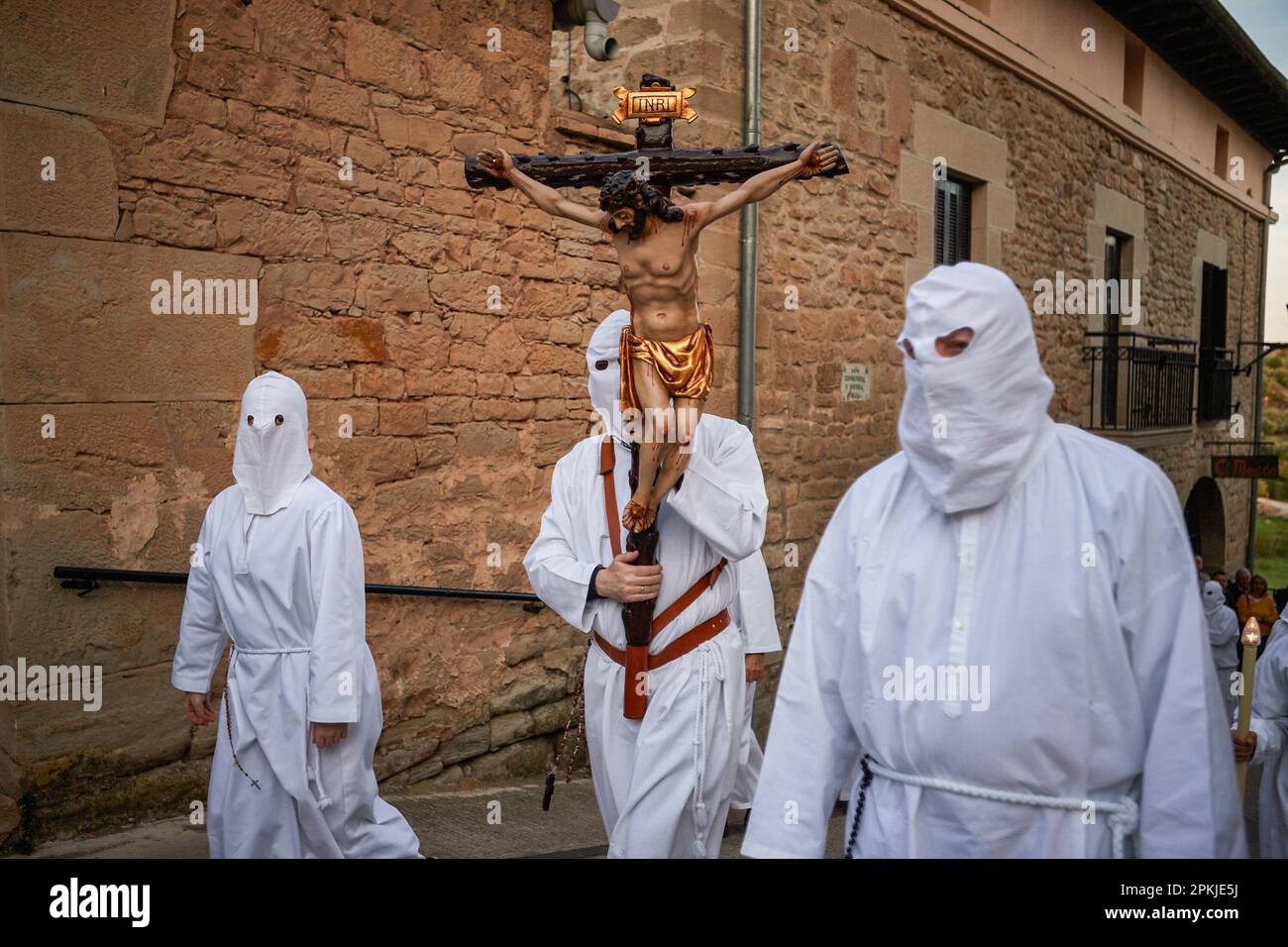 Un penitente della Confraternita della Santa de la vera Cruz porta una croce di Gesù Cristo attraverso le strade di Torres del Río, Navarra, Spagna. La Confraternita di Santa de la vera Cruz celebra una caratteristica processione nella settimana Santa a Torres del Río, Navarra, Spagna, nella quale i penitenti sono vestiti di bianco, facendo una piccola parte del Camino de Santiago, In cui portano una croce che un penitente rompe il silenzio della notte battendo al suono delle orme, mentre altri membri della fraternità portano la Virgen de la dolorosa. Foto Stock