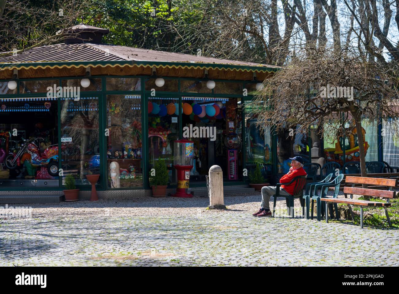 ROM, Italien, Apr. 2023 Ein Kiosk auf der Piazza Garibaldi, ein alter Mann auf einem Stuhl in der Sonne Foto Stock