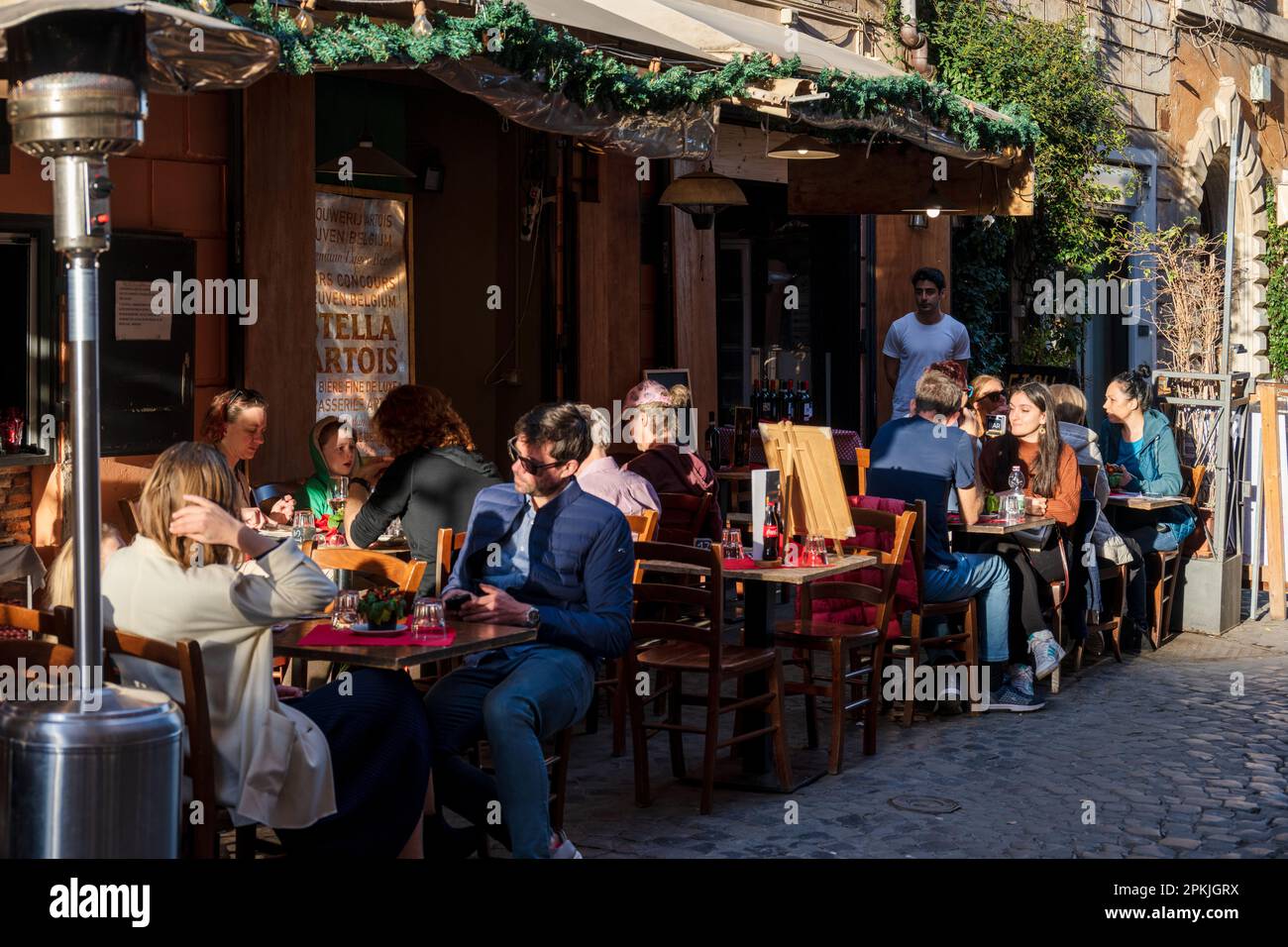 ROM, Italien, Apr. 2023 Straßenszene an einem warmen Frühlingstag Menschen genießen die Frühlingsluft in der Außenanlage eines Restaurantes in Trastev Foto Stock