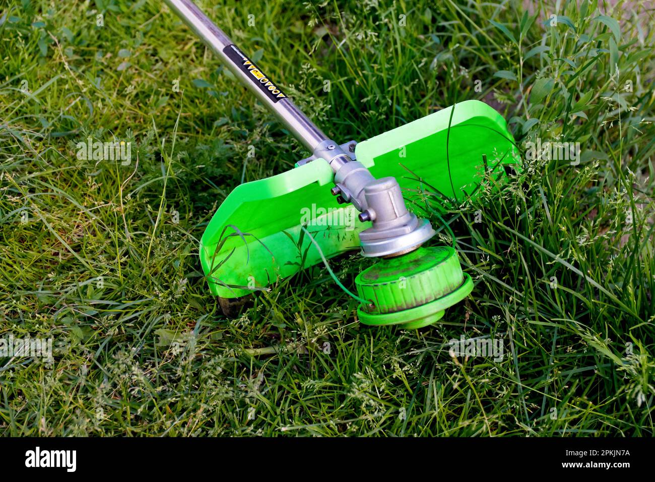 Defocalizzazione del tagliaerba. Un uomo che falciava l'erba. Vista esterna di un rasaerba che taglia erba in uno sfondo naturale sfocato. Lavori di casa. Taglierina ed Foto Stock