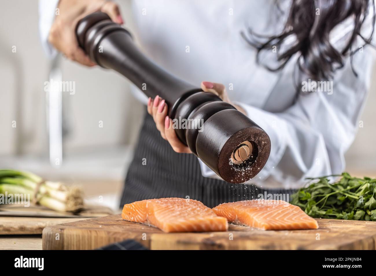 Un macinacaffè viene utilizzato da uno chef per condire il salmone in una cucina del ristorante. Foto Stock