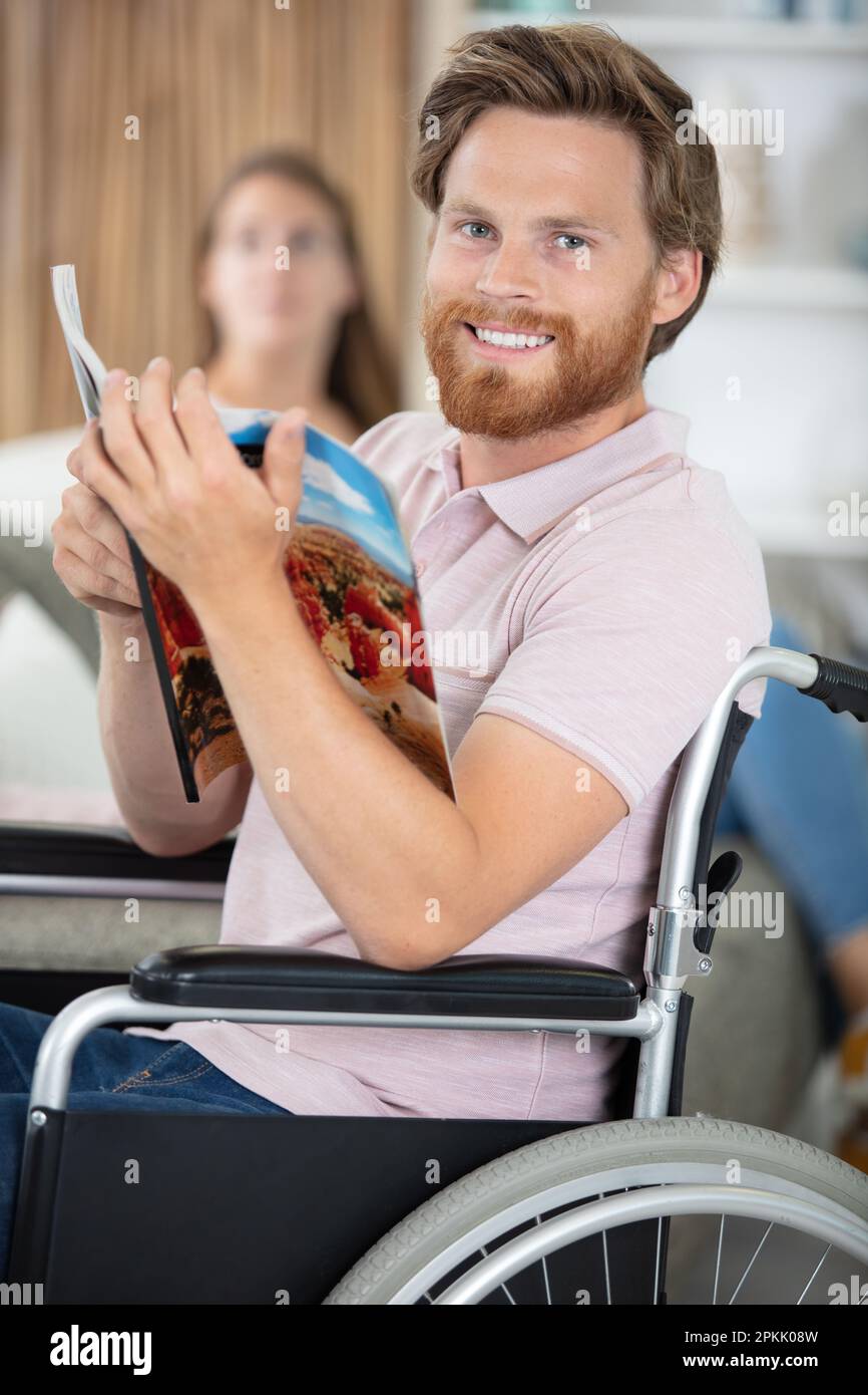 uomo portatore di handicap con un opuscolo di viaggio Foto Stock