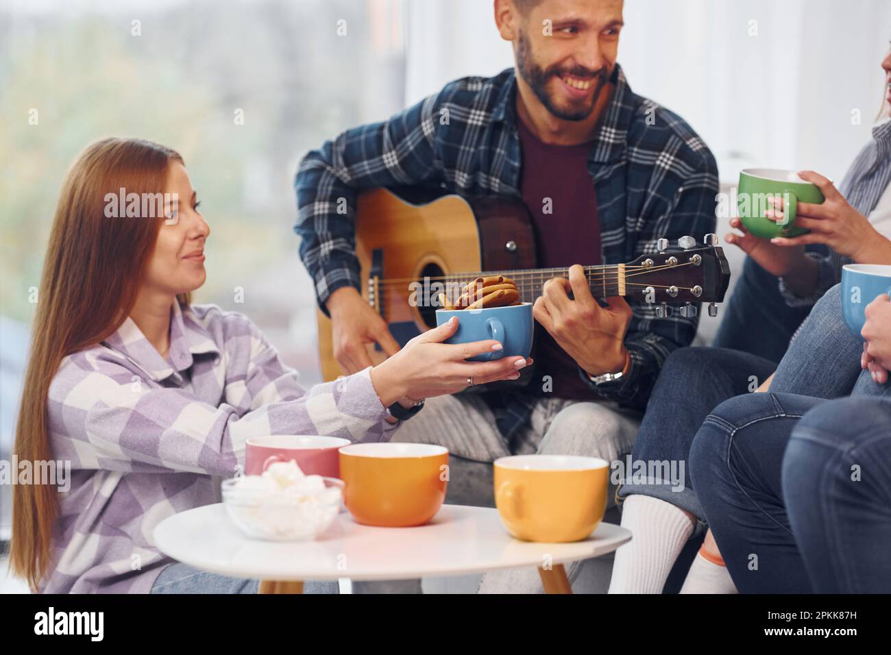 L'uomo suona la chitarra acustica. Gruppo di amici hanno partito insieme all'interno Foto Stock