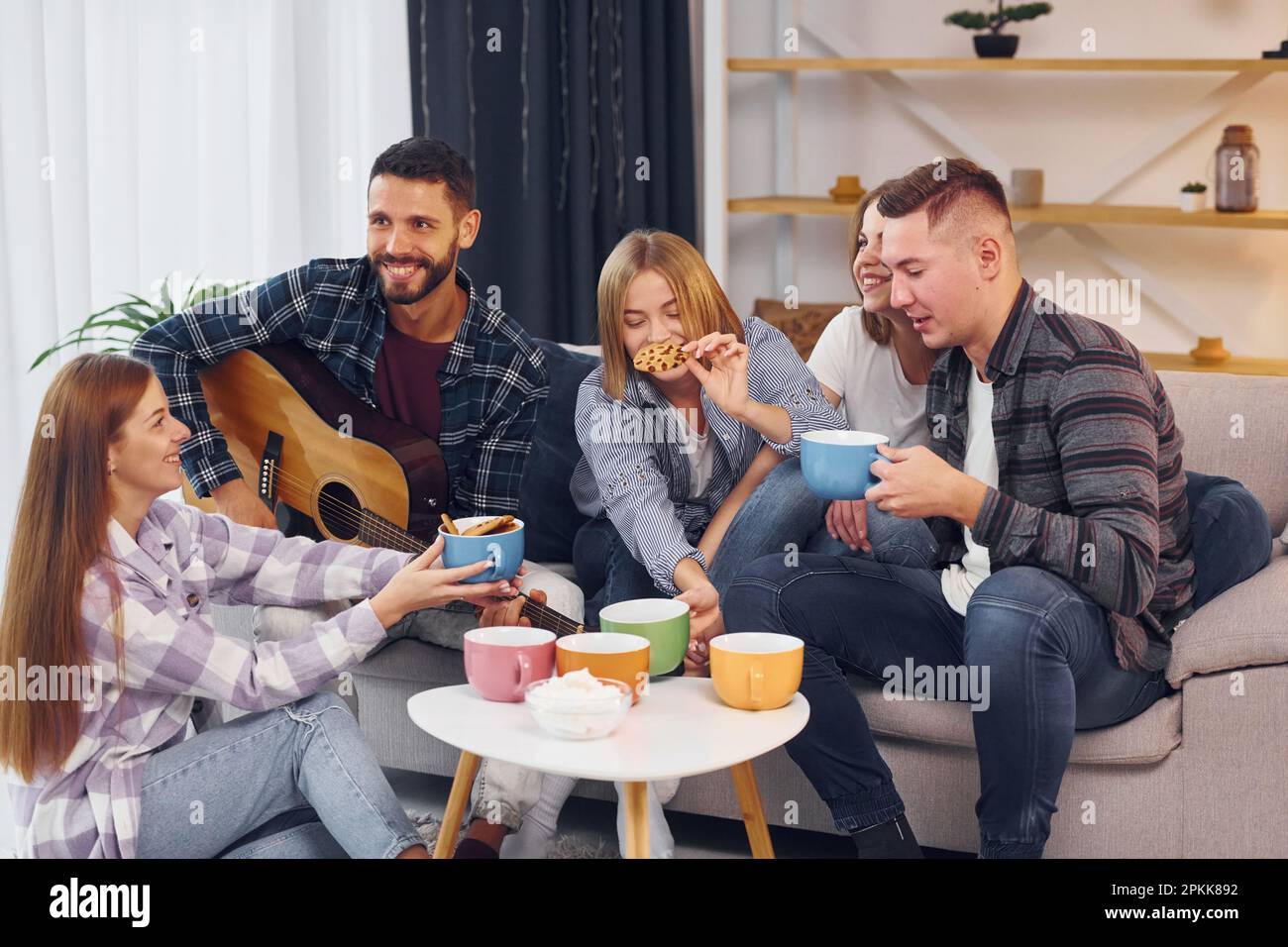 L'uomo suona la chitarra acustica. Gruppo di amici hanno partito insieme all'interno Foto Stock