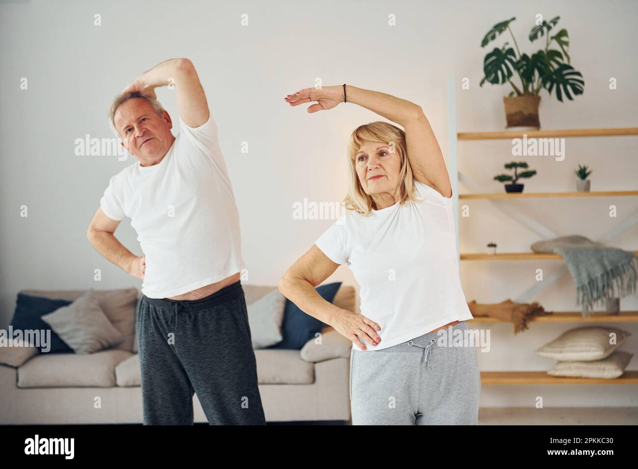 Fare stretching. L'uomo anziano e la donna sono insieme a casa. Foto Stock