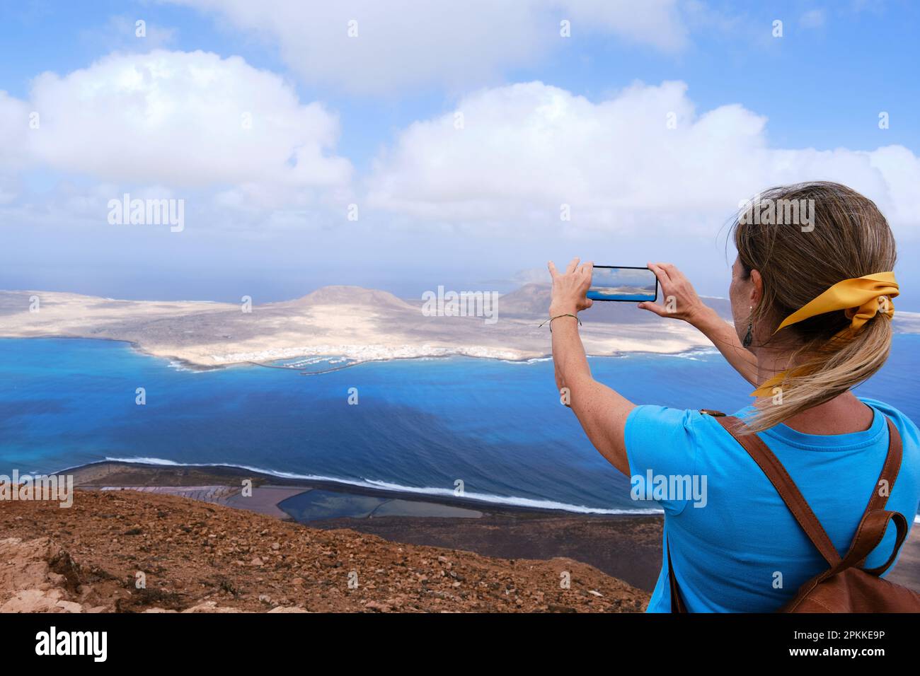 Una donna che fotografa l'isola la Graciosa con il suo smartphone. Lanzarote, Isole Canarie. Foto Stock