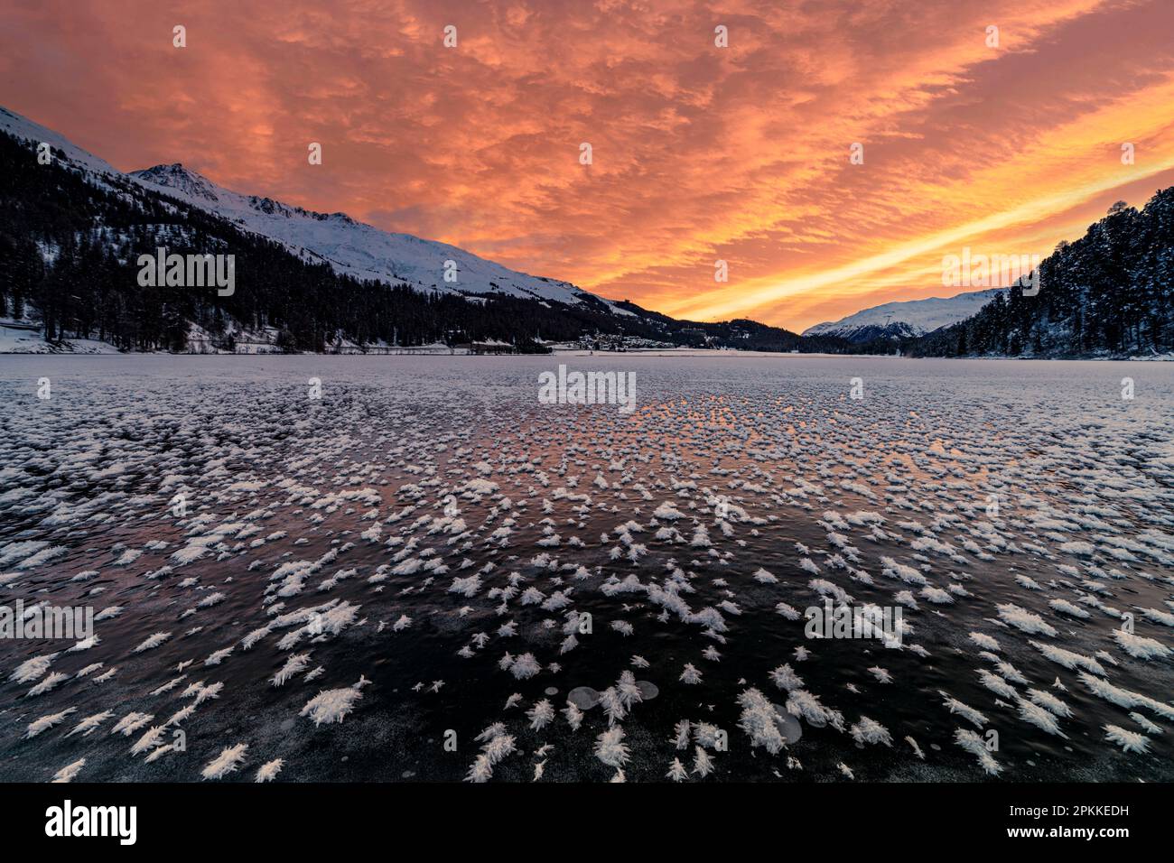 Cielo acceso all'alba sul lago ghiacciato Champfer coperto di fiori di ghiaccio in inverno, Engadina, Cantone di Graubunden, Svizzera, Europa Foto Stock