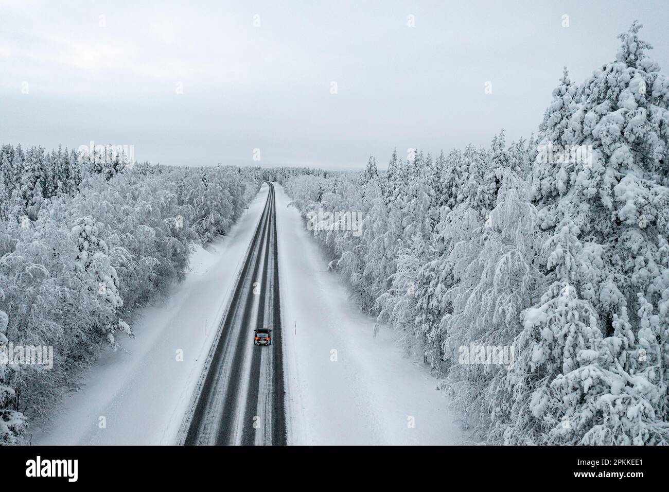 Vista dall'alto dell'auto che guida su strade ghiacciate nella foresta innevata, in Lapponia, Finlandia, Europa Foto Stock